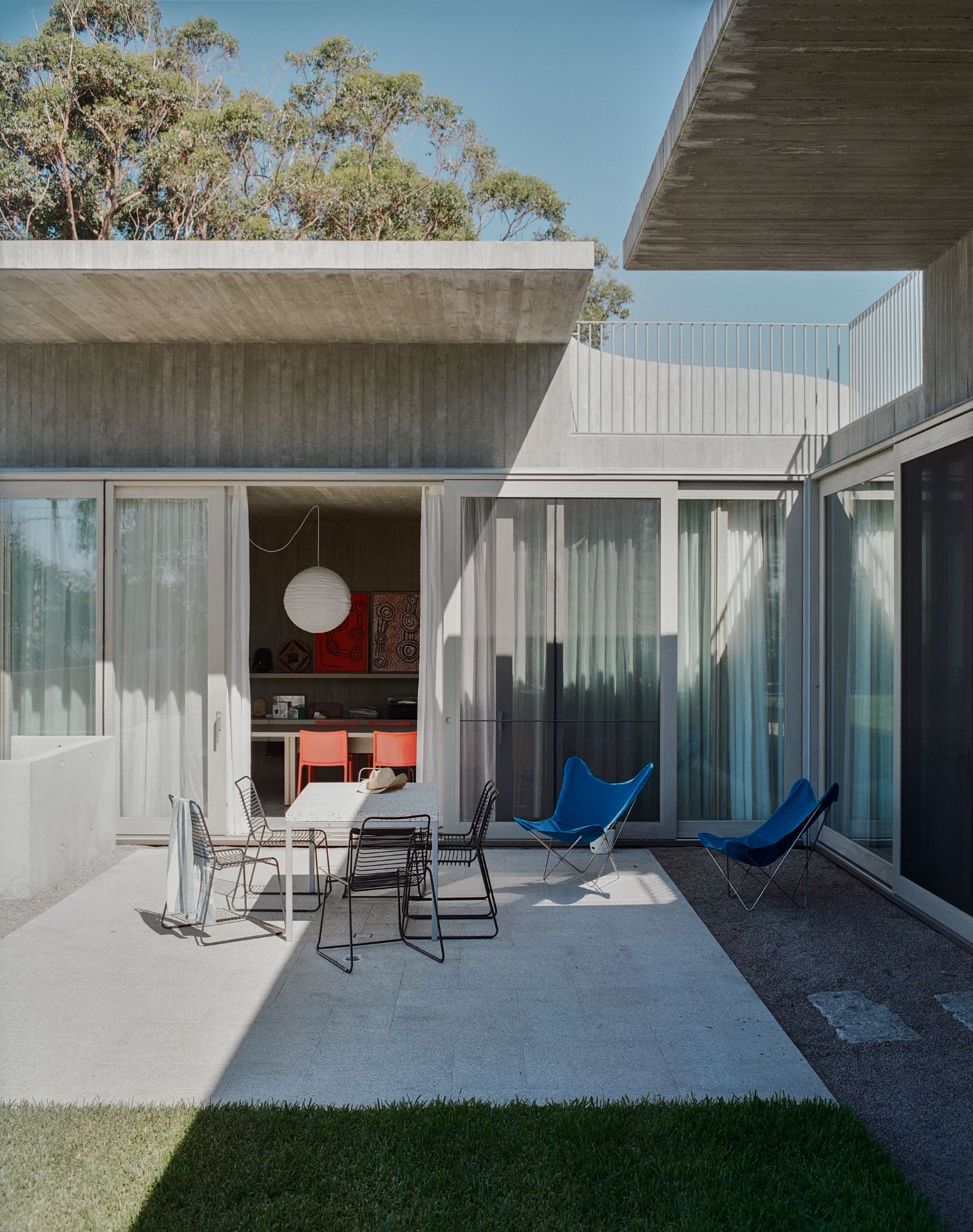 Mori House by Aires Mateus + MAArchitects — The courtyard elevation frames a lived-in moment across monolithic concrete slabs and continuous glazing.