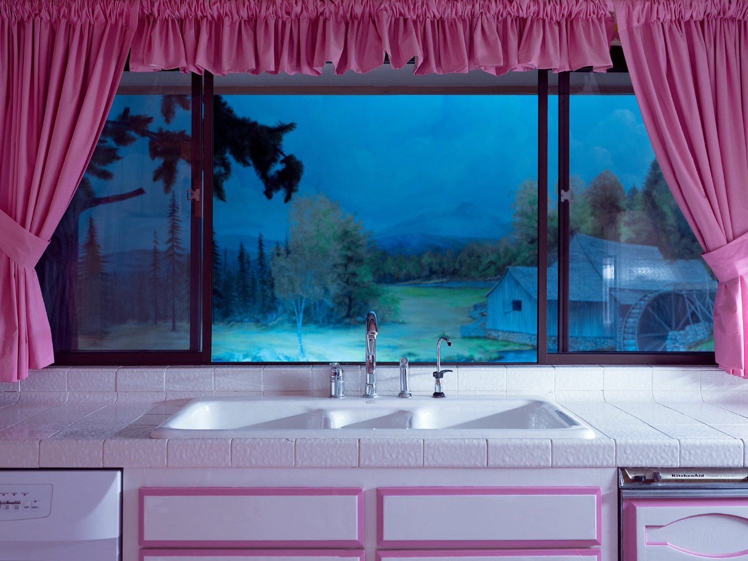 What to do with a Million Years by Juno Calypso — A kitchen sink positioned beneath a large-format painted mural depicting a twilight forest landscape with distant cabin and water.