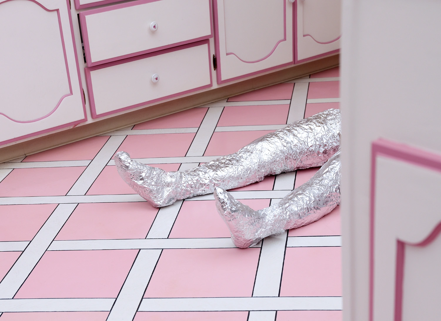 What to do with a Million Years by Juno Calypso — Silver-wrapped feet rest on a pink and white geometric tile floor within the underground bunker.