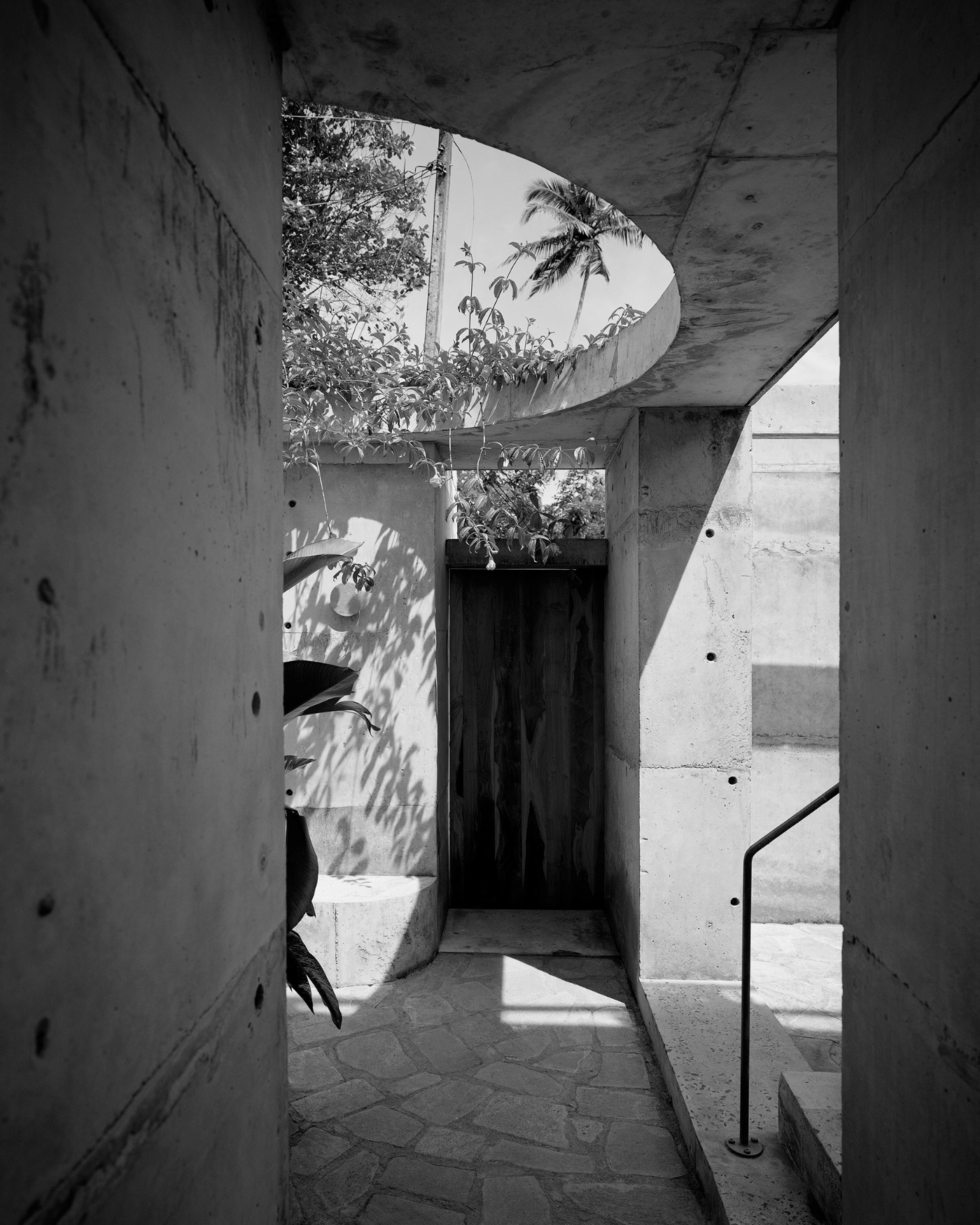 057 Guesthouse Hiriketiya by Atelier Abraha Achermann — A narrow concrete passage frames the guesthouse's layered spatial strategy.