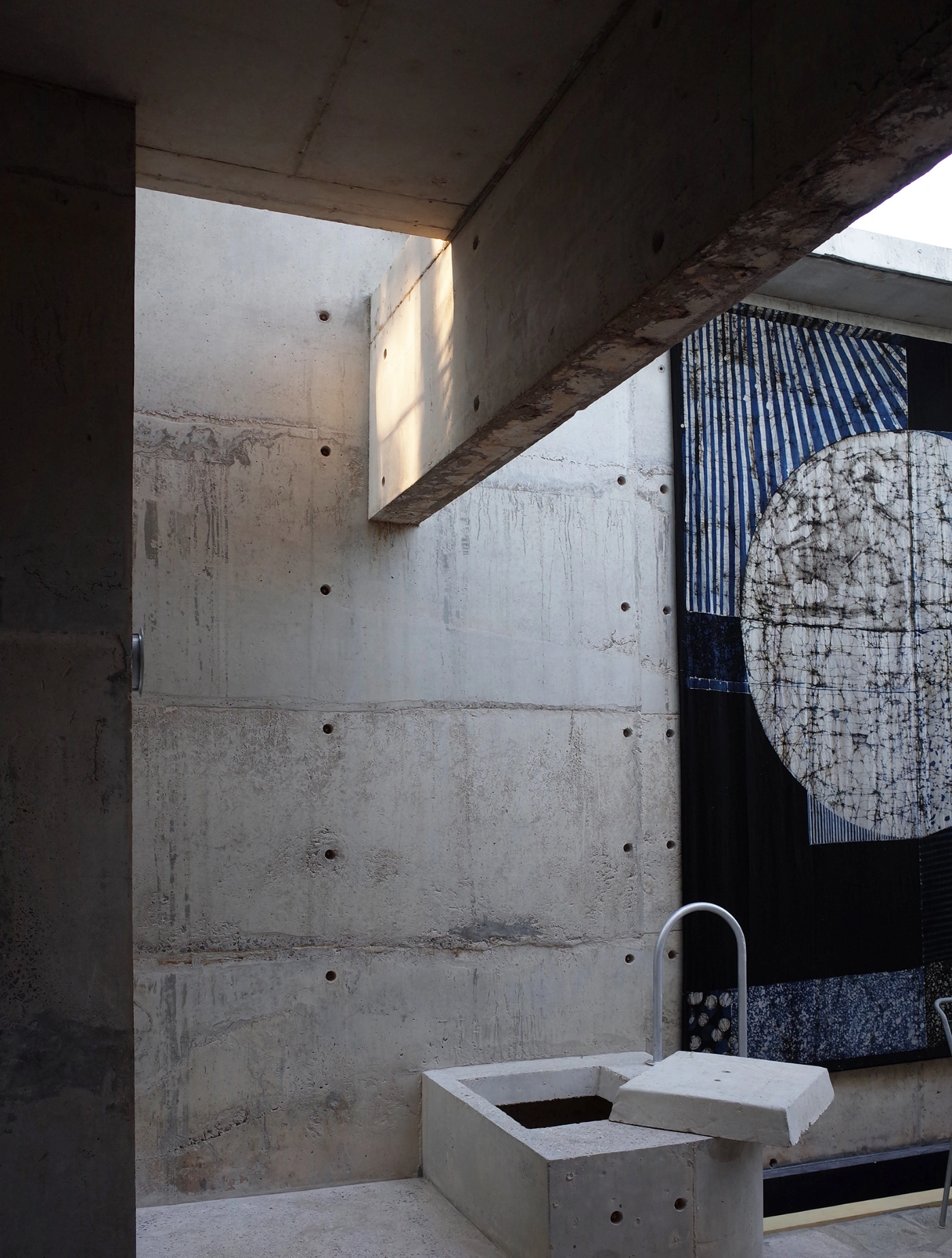 057 Guesthouse Hiriketiya by Atelier Abraha Achermann — A concrete ablution basin with paired rectangular voids dominates the foreground of this open-air bathroom court.