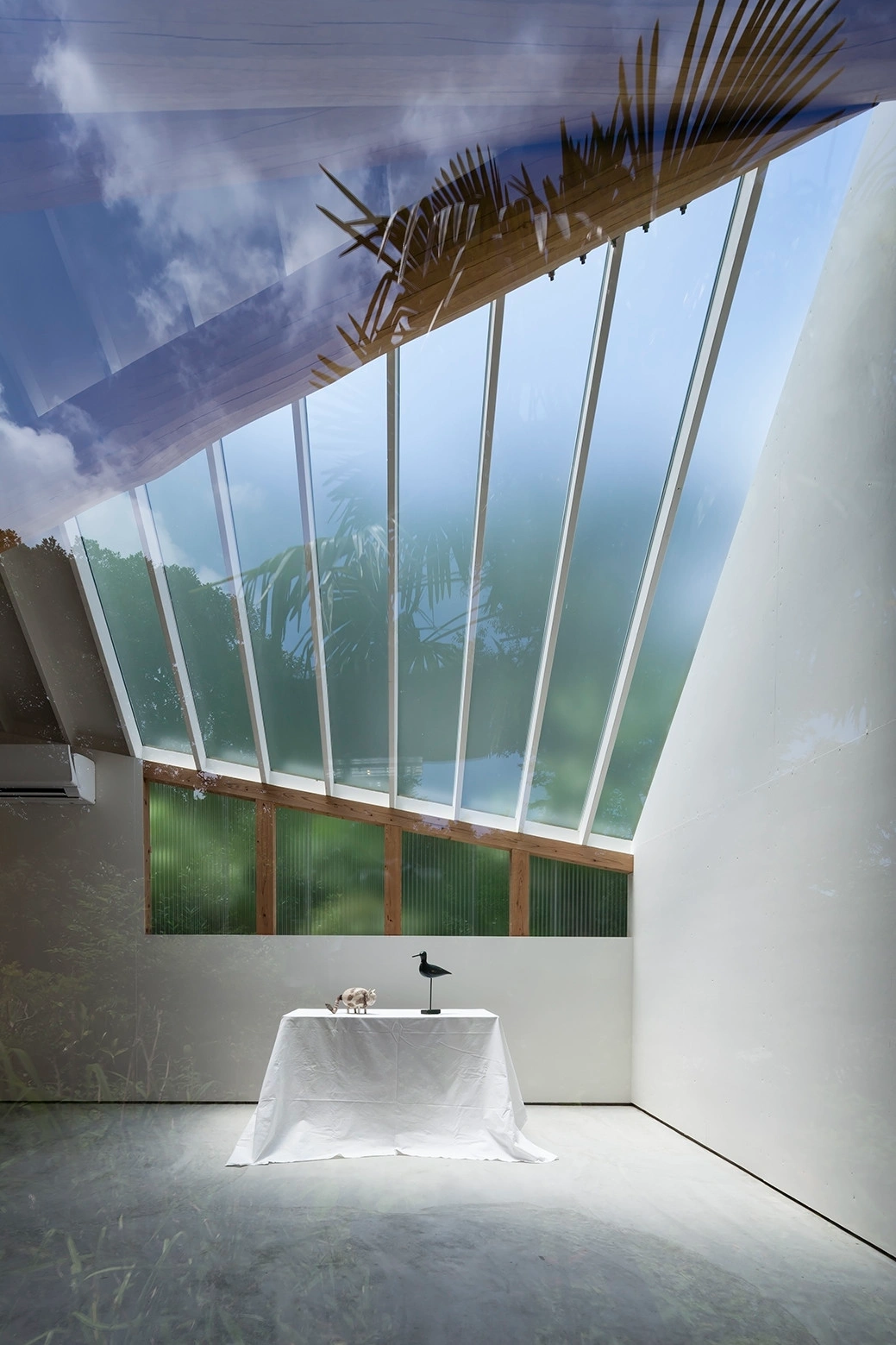 Photography Studio by FT Architects — A single-room photography studio captured from ground level, revealing the interior spatial strategy through transparent materials and structural logic.
