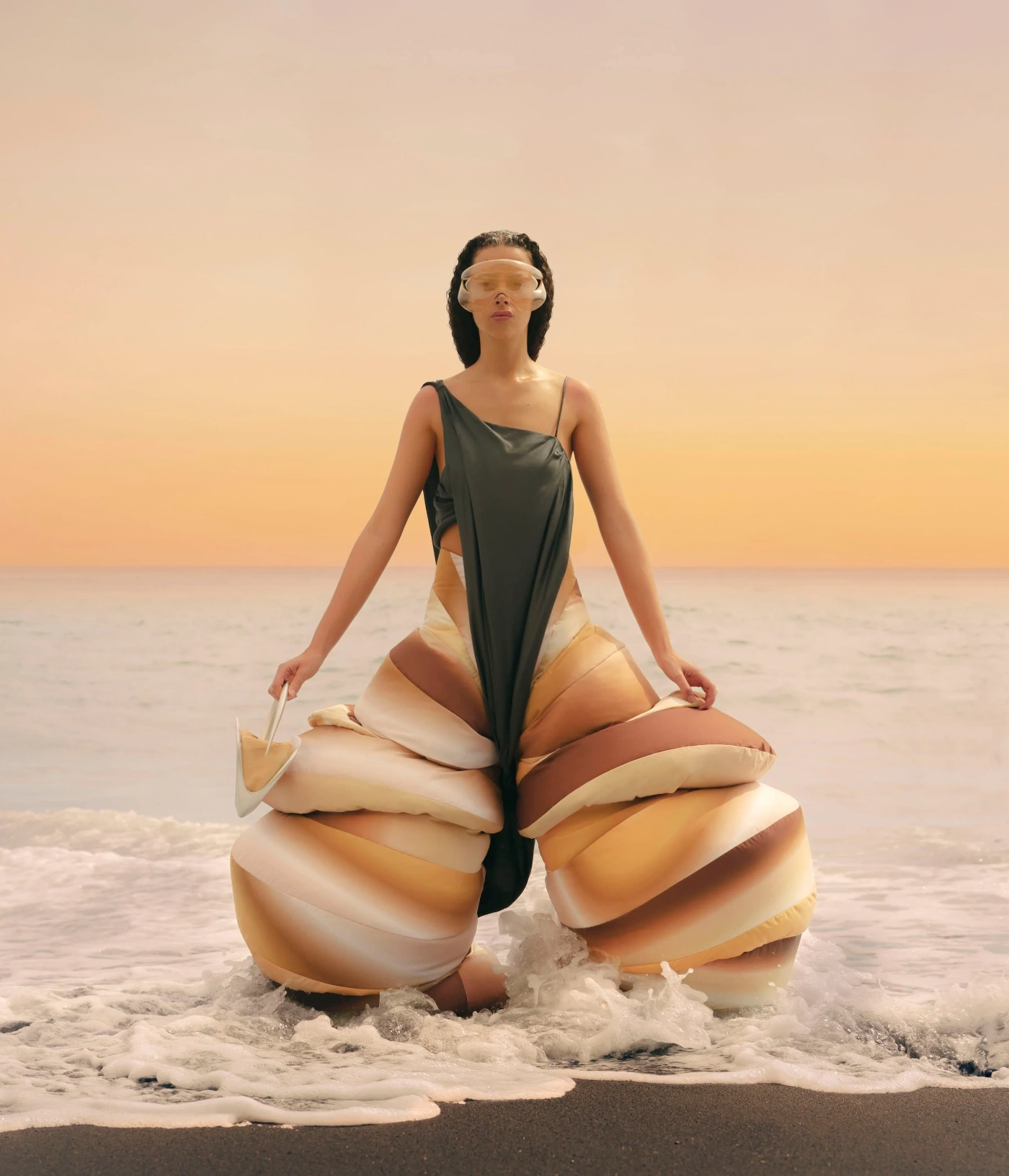 'Terranova' Graduate Collection by Izzy Du — Du's Terranova collection presents an oversized, cocoon-like fabric garment in cream and terracotta tones, positioned in shallow coastal waters during...
