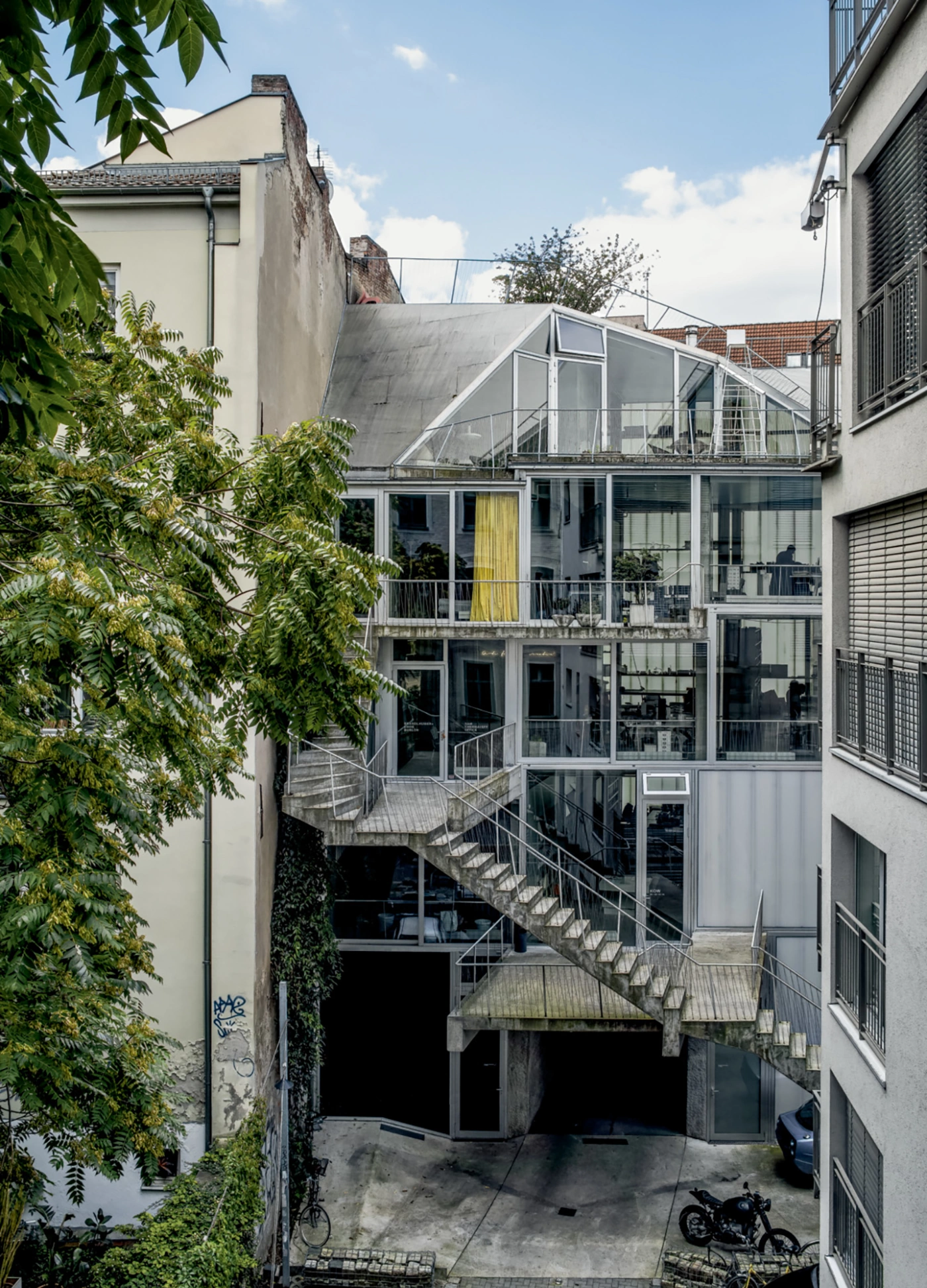 Brunnenstrasse 9 by Brandlhuber+ by Brandlhuber & Emde & Burlon — A diagonal concrete cantilever staircase with steel cable railings cuts across the facade of this densely packed urban infill project, creating the primary...