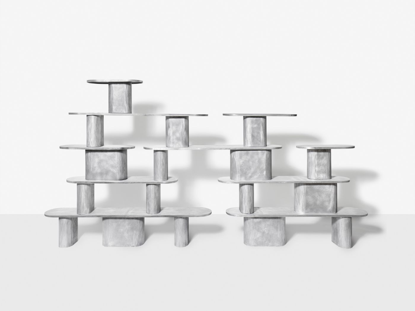 'Structure For Use' by Jeonghwa Seo — A modular shelving system composed of cast concrete cylindrical supports in varying diameters, paired with curved concrete shelf elements and speckled...