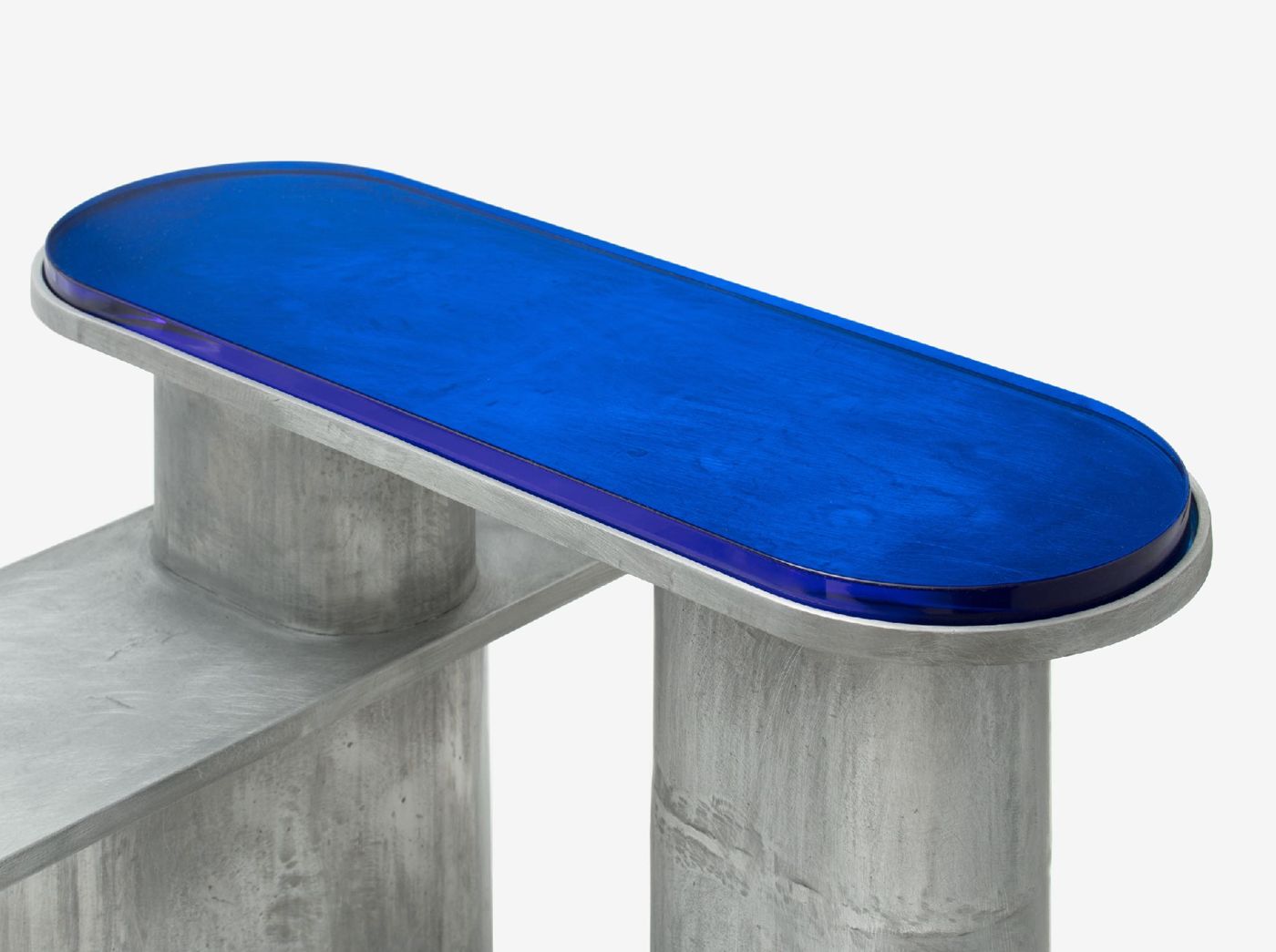 'Structure For Use' by Jeonghwa Seo — A cast concrete bench with cylindrical legs supports an elongated oval top finished in vibrant cobalt blue with visible dark aggregate flecks and a dark...