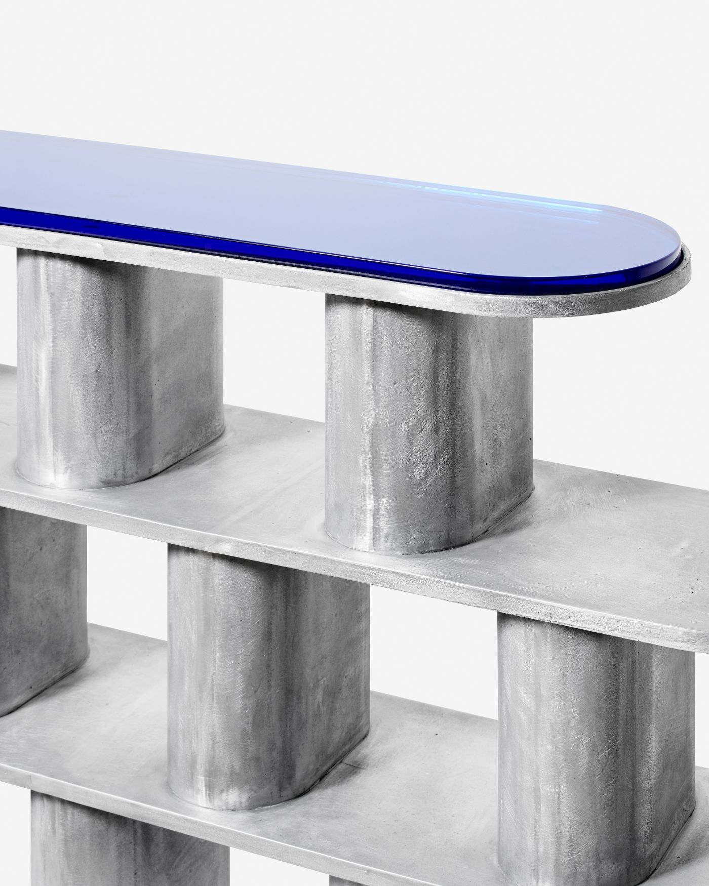 'Structure For Use' by Jeonghwa Seo — A cantilevered bench from Jeonghwa Seo's Structure For Use series, featuring a curved glass top with dark blue edge banding supported by two cylindrical...