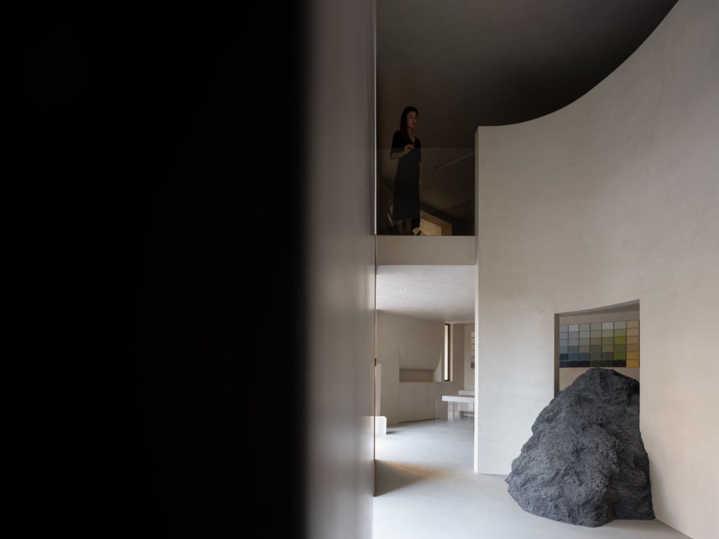 Novacolor Store by LICO Design — A double-height interior volume showcases LICO Design's material contrast strategy through juxtaposed elements: an unfinished granite boulder sits...