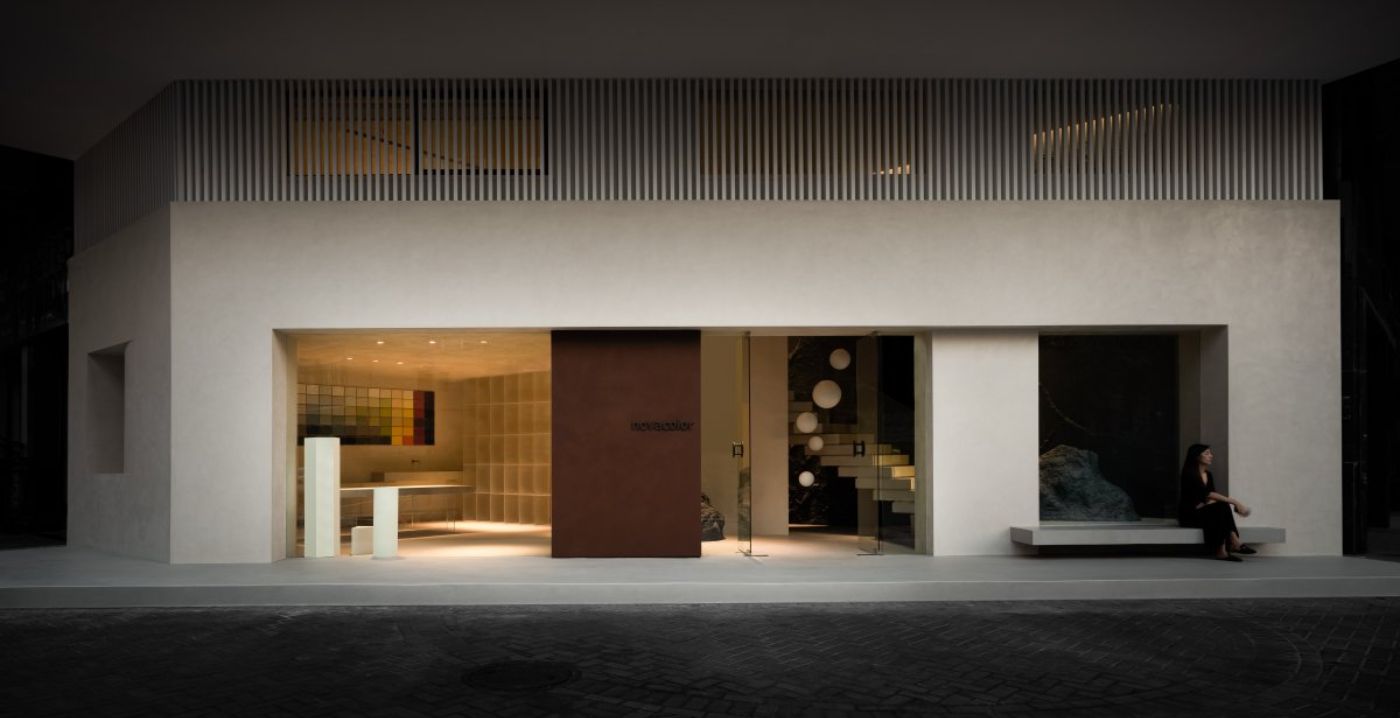 Novacolor Store by LICO Design — The Novacolor Store frontage presents a minimalist retail threshold with a continuous white plaster facade interrupted by recessed display and entry zones.
