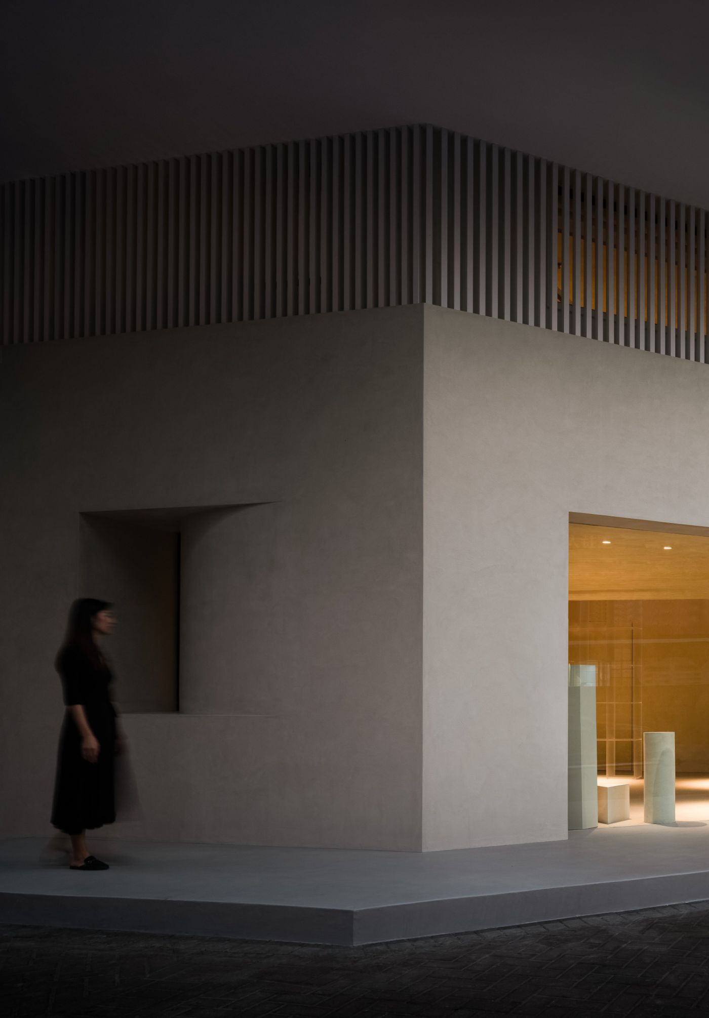 Novacolor Store by LICO Design — A corner of the Novacolor Store features a volumetric white plaster pavilion with a gridded panel door on the left facade.