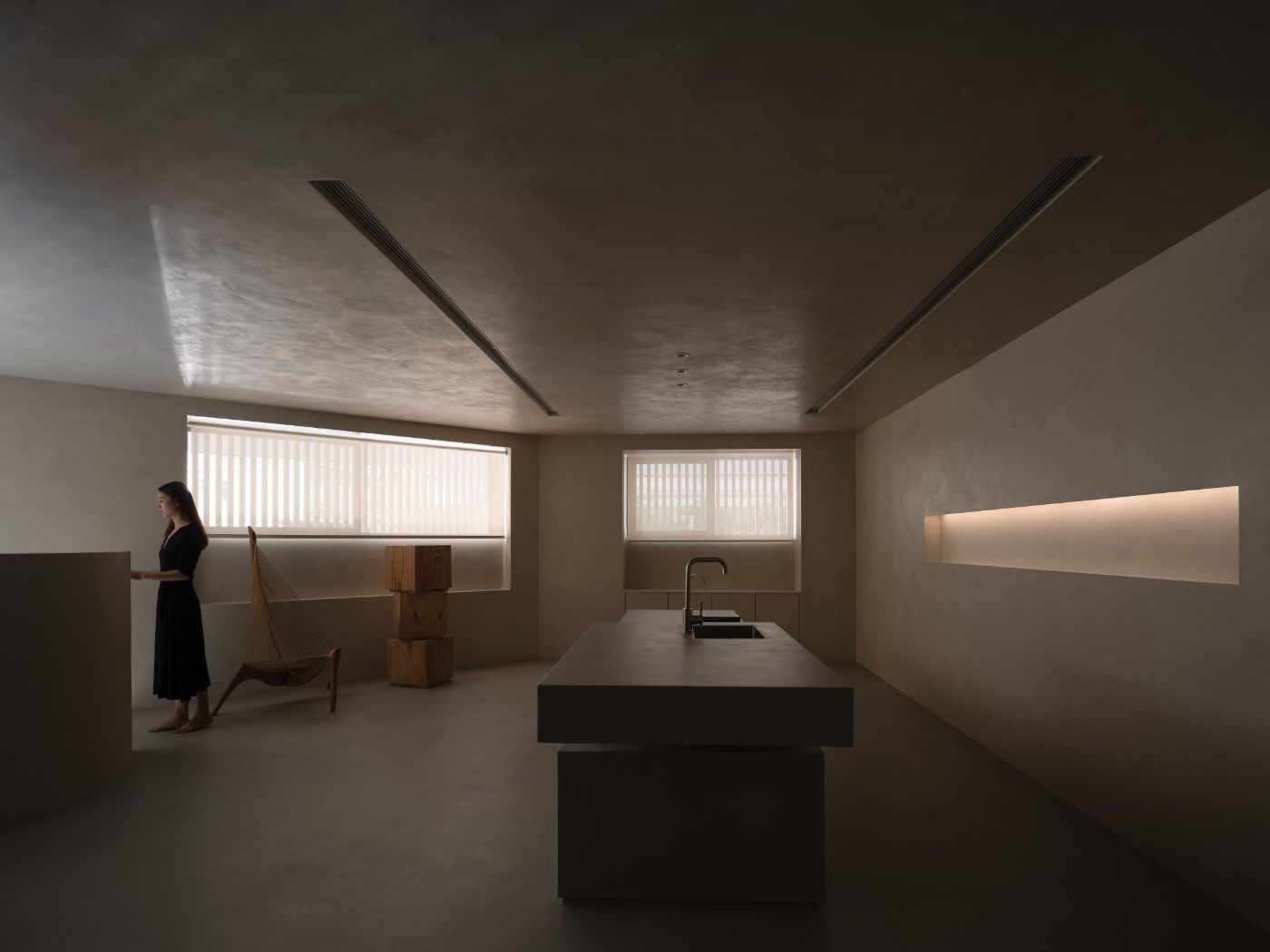 Novacolor Store by LICO Design — A minimalist interior rendered in monochromatic plaster and concrete, divided by angled soffit lines that segment the ceiling plane.