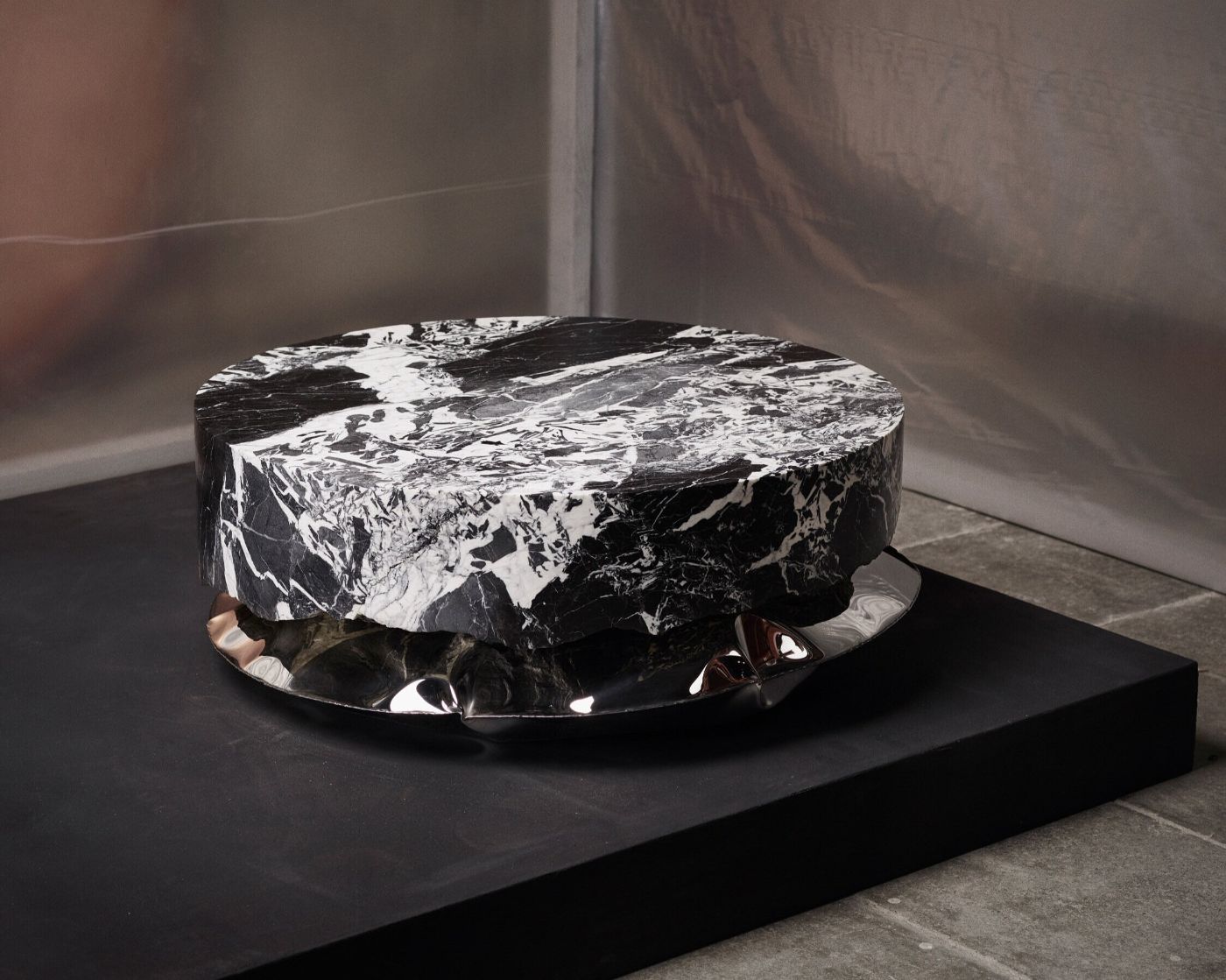 In Hale Wallpiece by Ben Storms — Ben Storms' inflated stainless steel cushion-form rests on a black platform, its surface creased and folded from the pressure-forming process against stone.