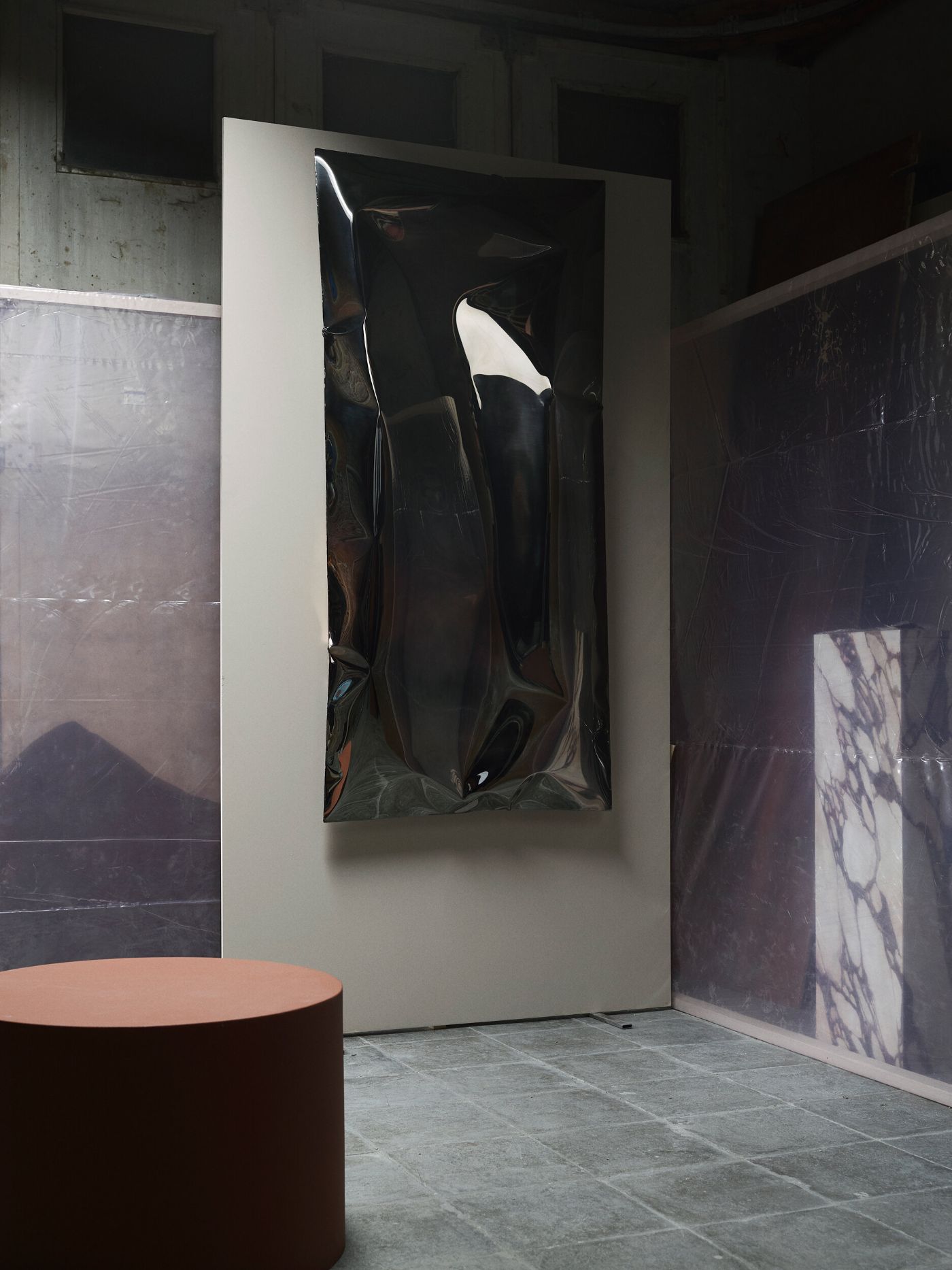 In Hale Wallpiece by Ben Storms — Ben Storms' inflated stainless steel wall-mounted cushion dominates the gallery space, its reflective surface fragmenting light across deep creases and...