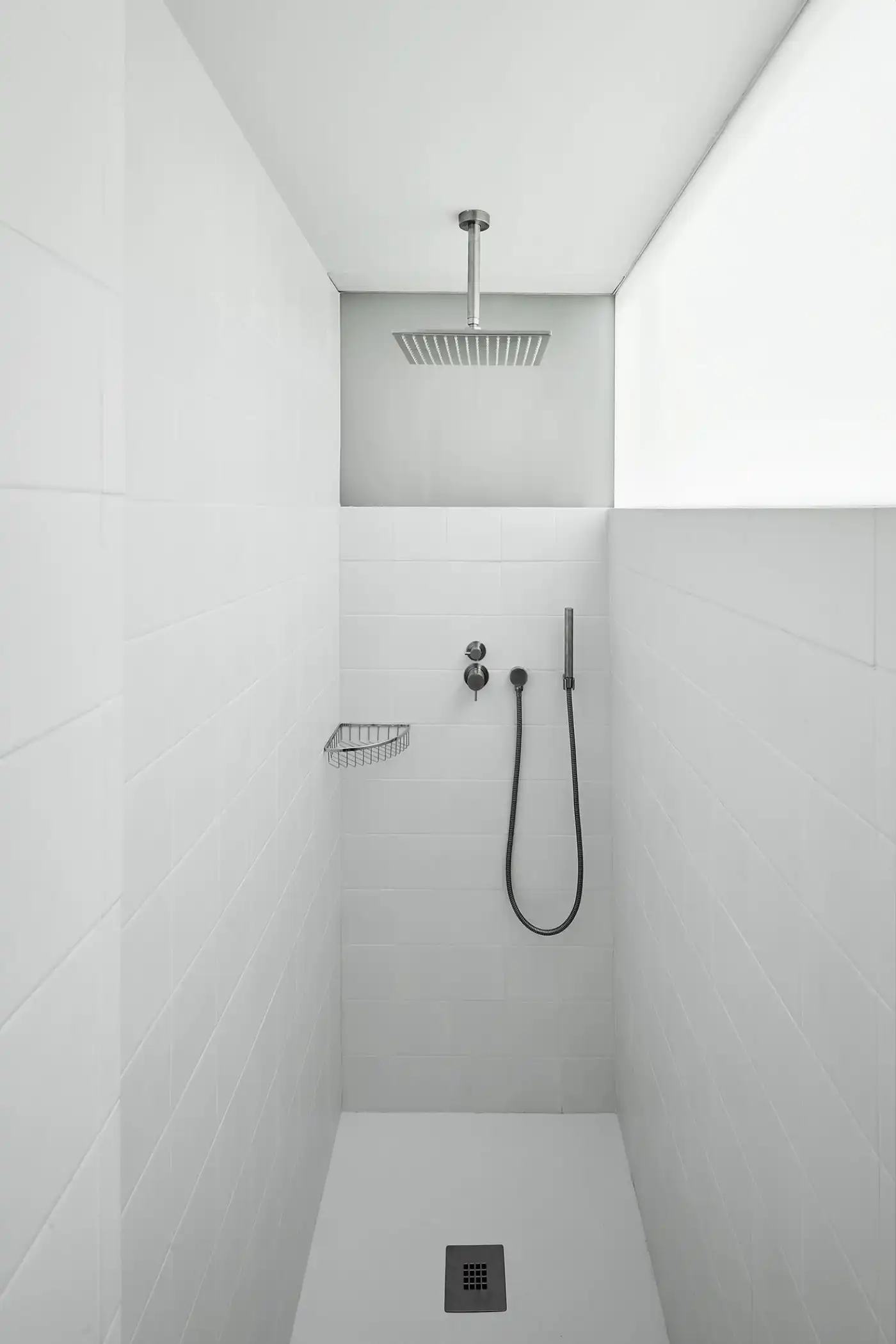 Flat in Eixample by Jaime Prous Architects — Vertical view of a narrow shower enclosure featuring white subway tile walls arranged in horizontal courses.