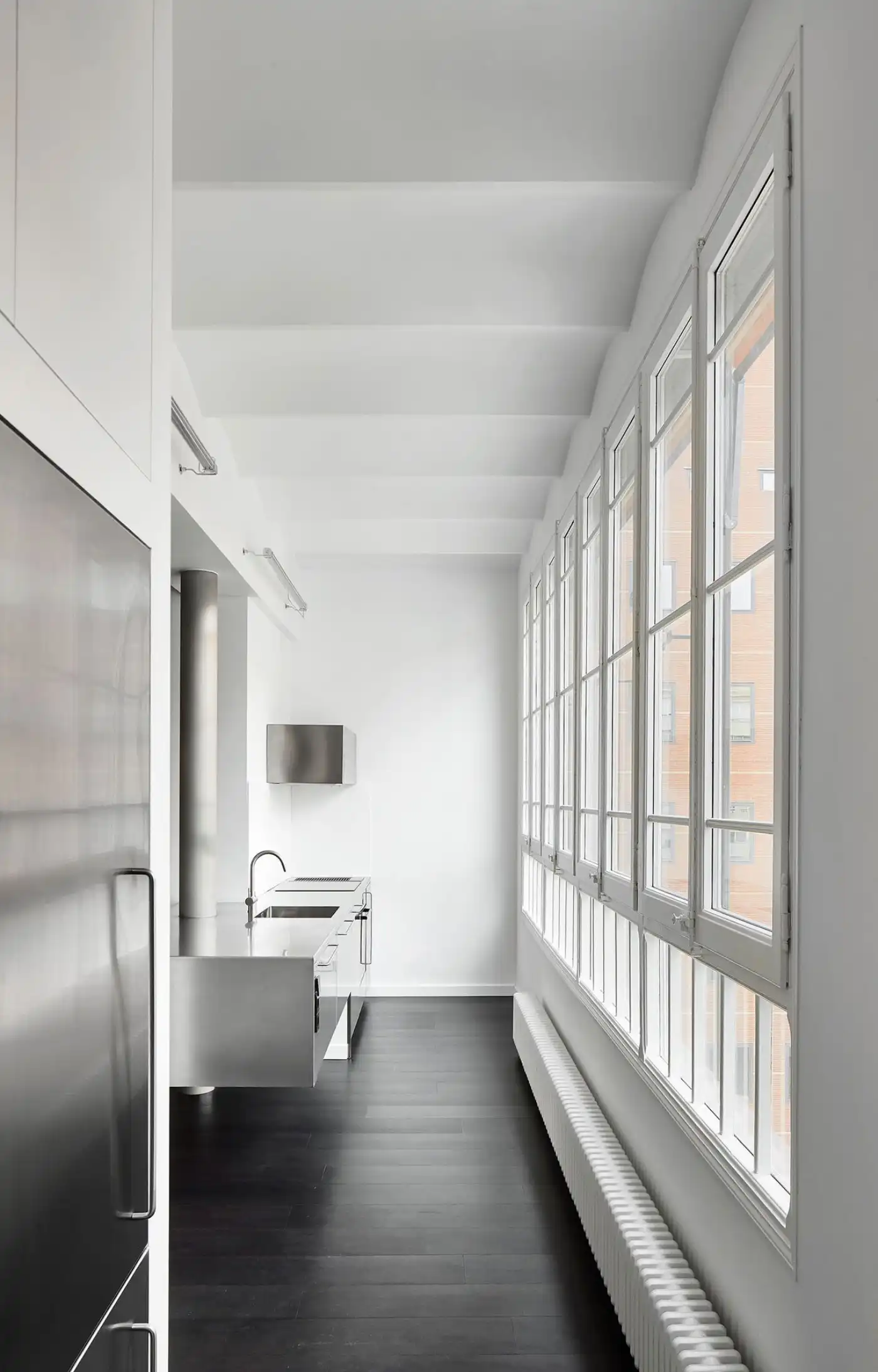 Flat in Eixample by Jaime Prous Architects — A galley kitchen stretches toward expansive west-facing windows in this Barcelona flat.