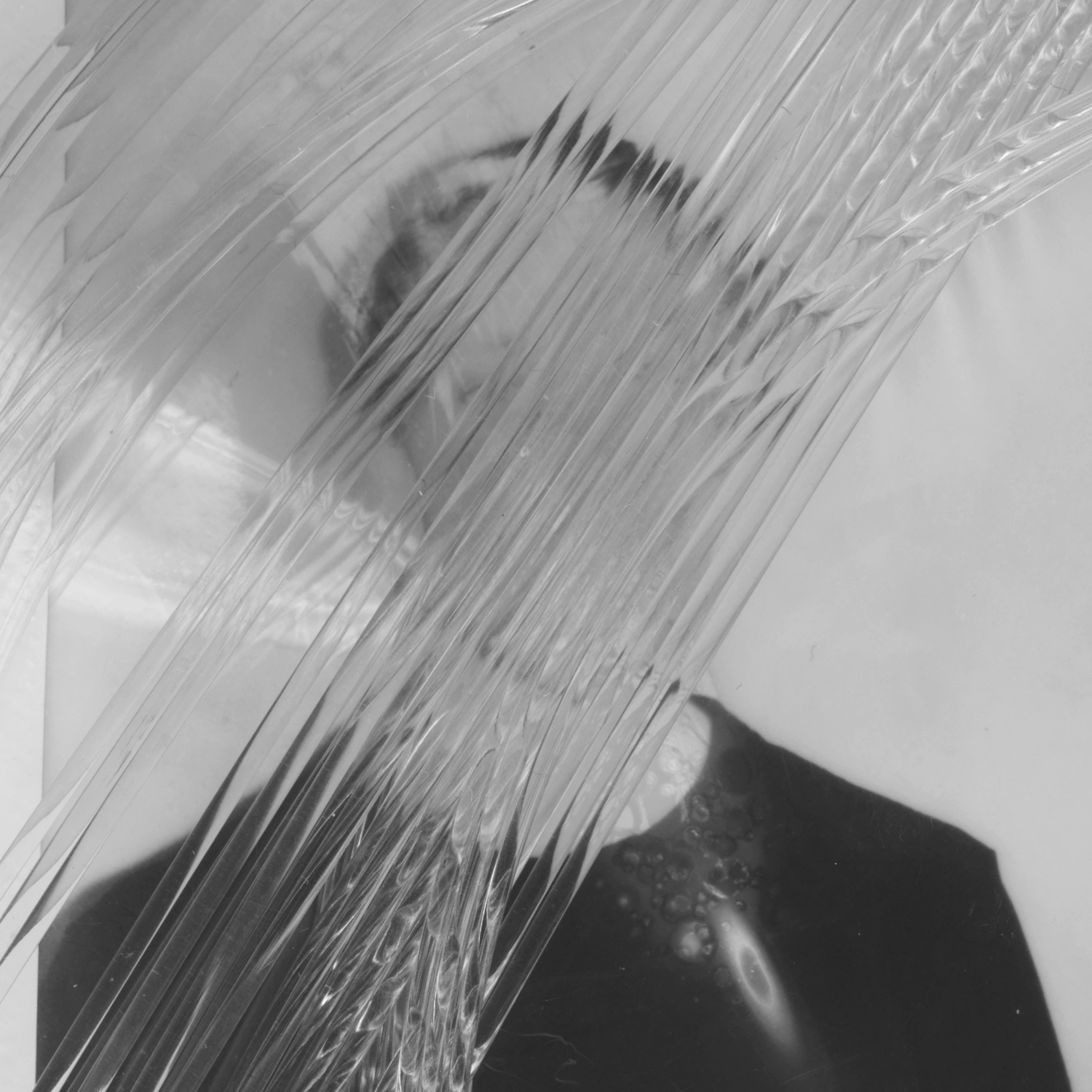 Privacy Portraits by Operator — A portrait obscured by vertical ribbed glass positioned between camera and subject, fragmenting facial features into parallel linear streaks.