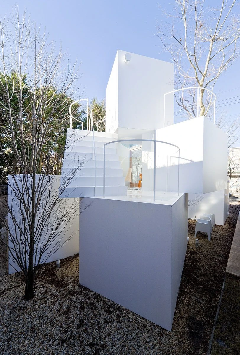 House Before House in Utsunomiya by Sou Fujimoto — A cubic residential volume elevated on a solid white rendered plinth, its upper section defined by stacked geometric forms with a circular aperture...