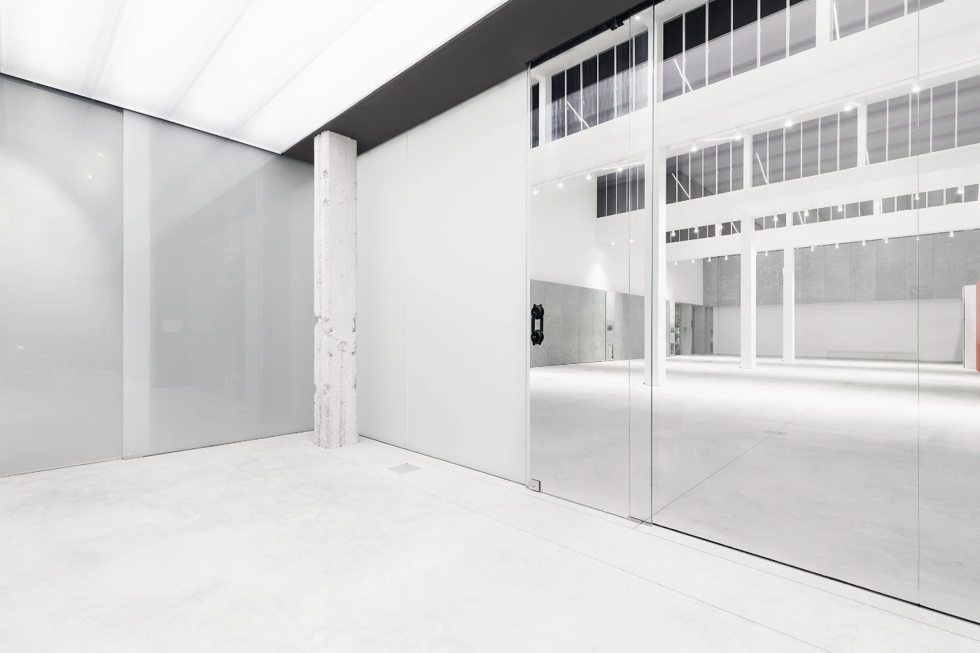 Spazio Maiocchi in Milan — A corridor within the former industrial warehouse stretches toward a glazed partition with diagonal cross-bracing.