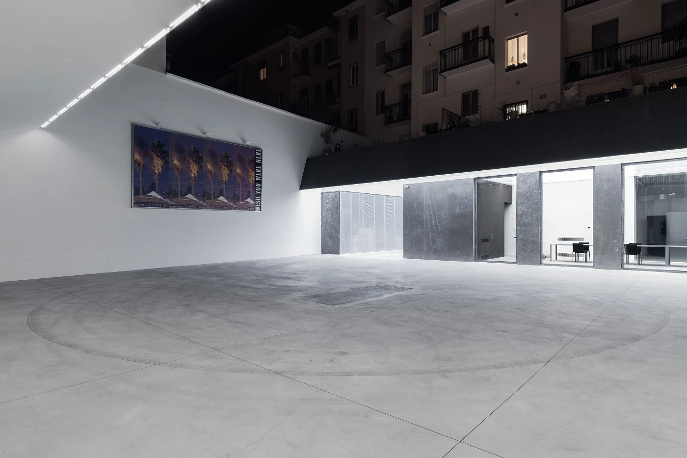 Spazio Maiocchi in Milan — A monolithic concrete floor anchors this exhibition space, its polished surface articulated by visible seams and a concentric circular pattern inscribed...