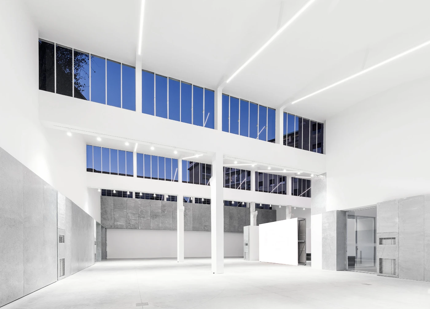 Spazio Maiocchi in Milan — A double-height interior volume demonstrates post-and-beam structural logic with white-painted columns supporting exposed ceiling planes.