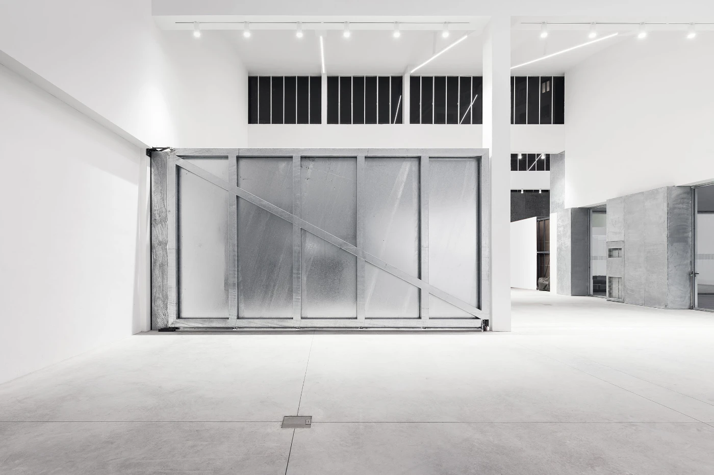 Spazio Maiocchi in Milan — A double-height gallery space with radiating linear ceiling elements that cast sharp shadows across the white ceiling plane, creating a geometric sunburst...