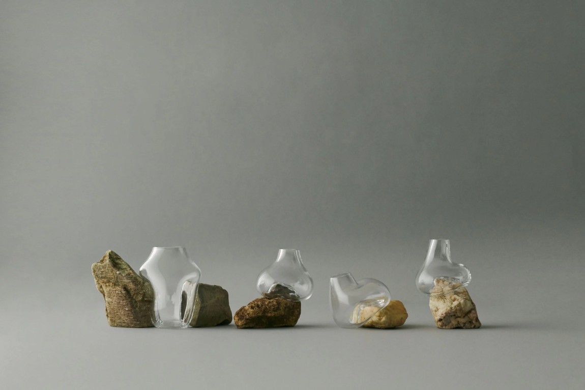 Vase Sculptures by Lætitia Jacquetton — Five mouth-blown glass vessels arranged in a linear composition, each cradling weathered stones collected from natural sources.
