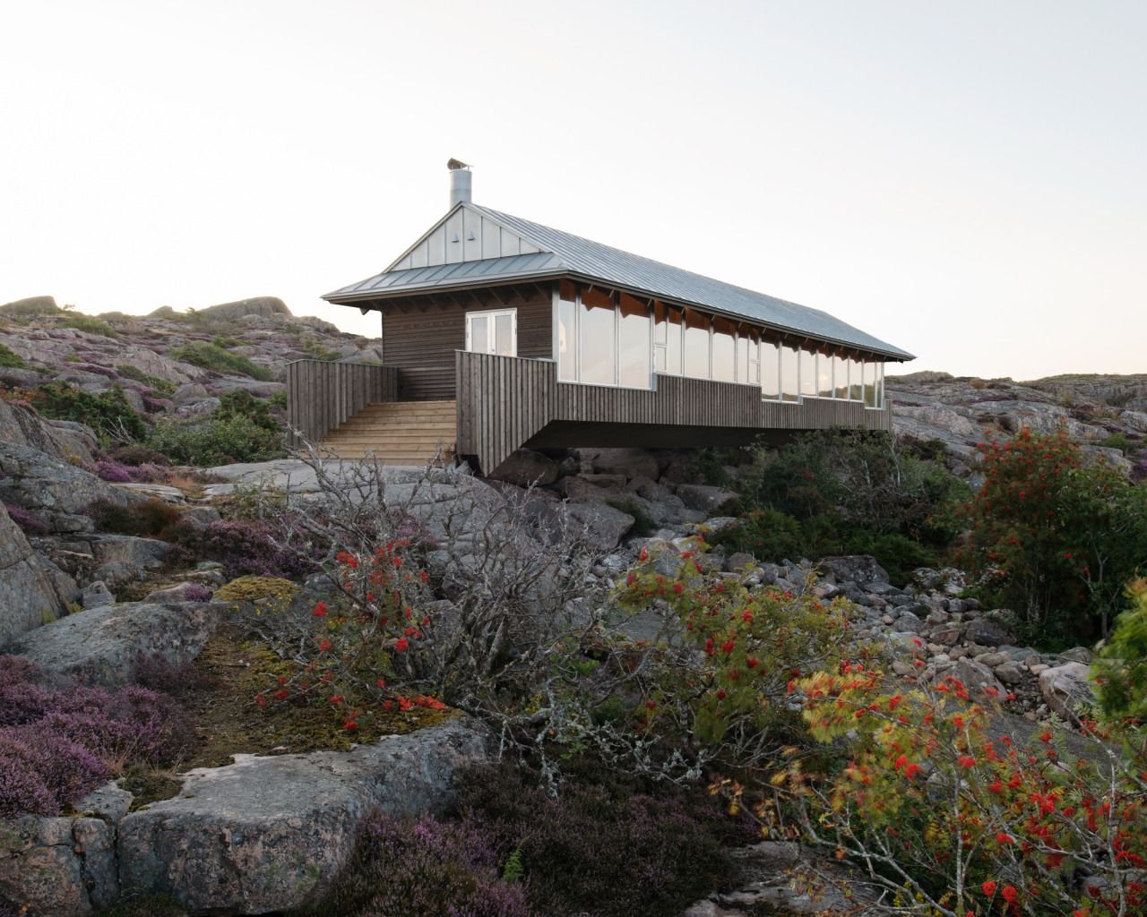 House Hamburgö by Manthey Kula — House Hamburgö spans a glacial landscape via two laminated timber arches, its load-bearing structure visible beneath corrugated metal cladding in weathered...