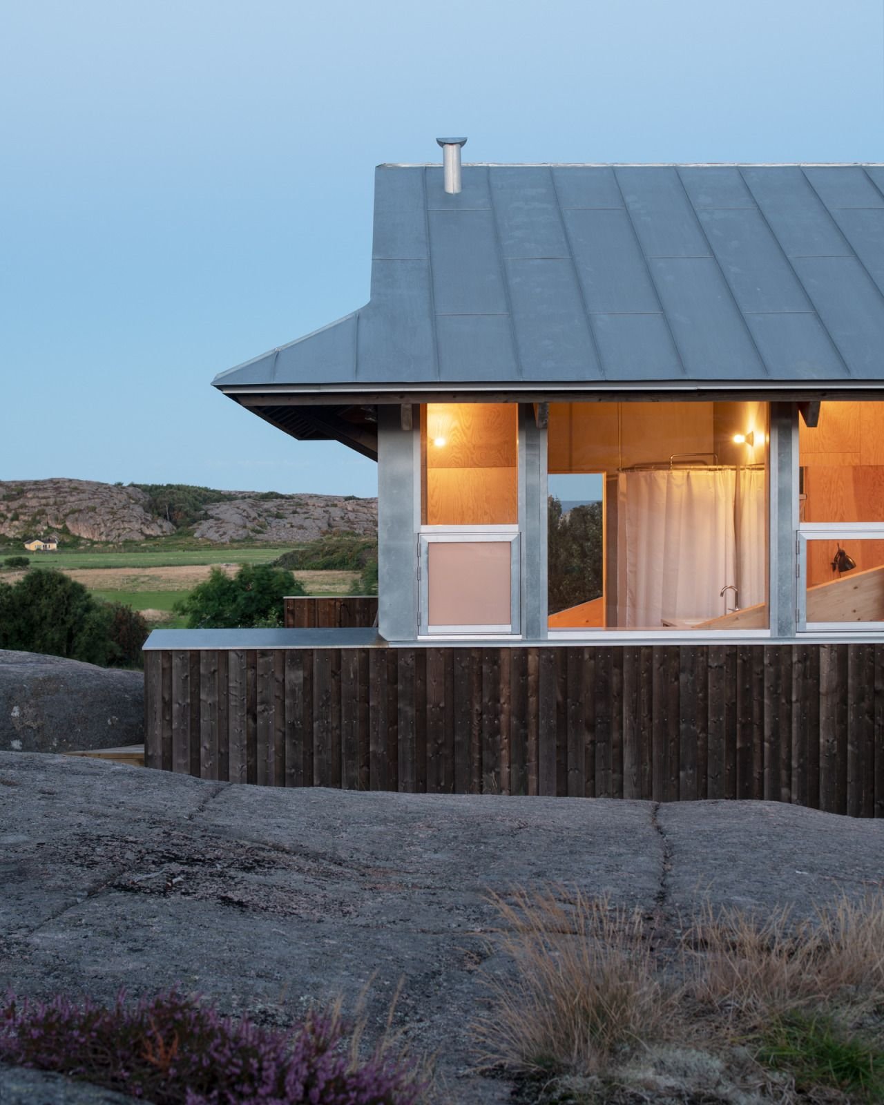 House Hamburgö by Manthey Kula — House Hamburgö captured at dusk presents its glazed facade illuminated against the darkening Swedish sky.