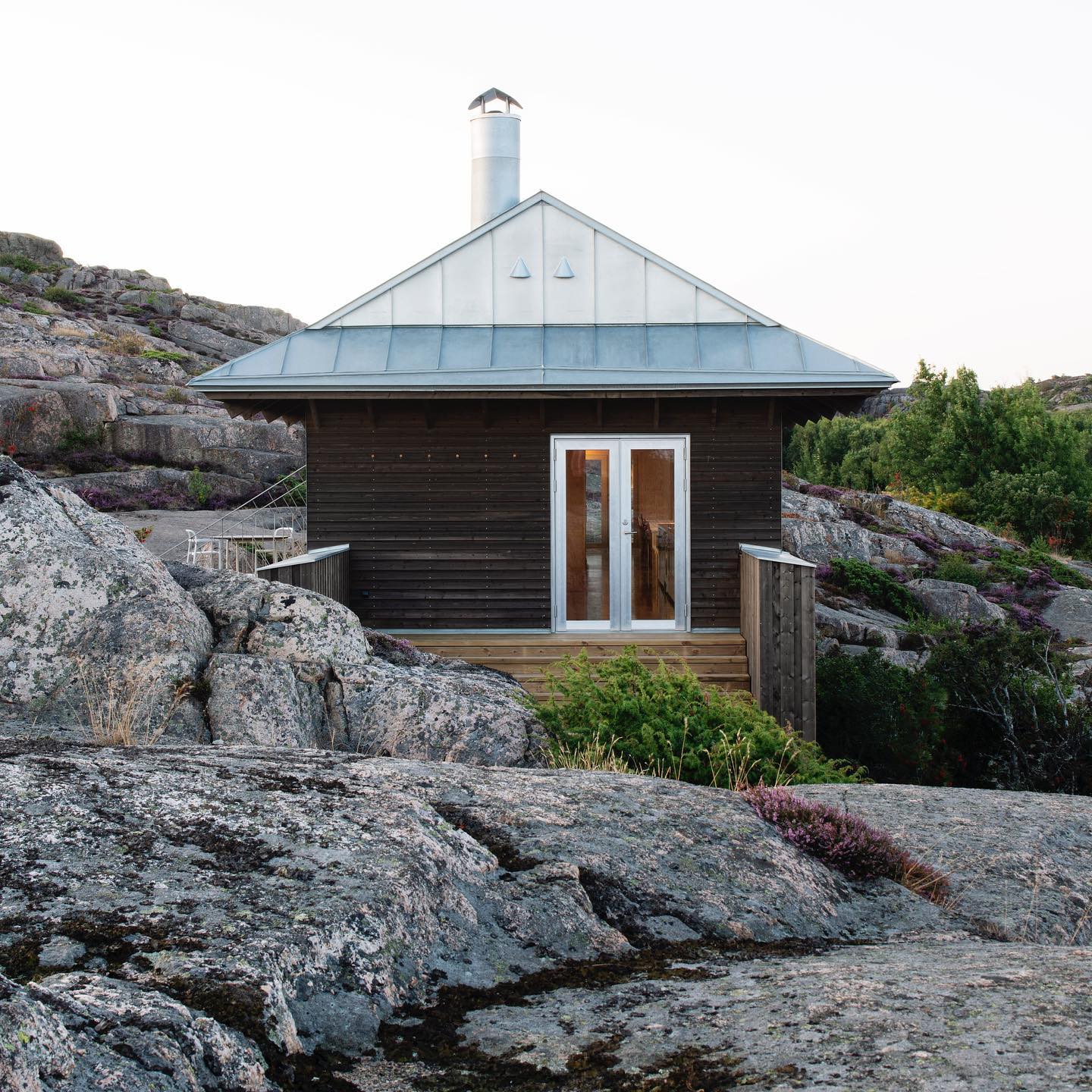 House Hamburgö by Manthey Kula — House Hamburgö bridges two granite bedrock plateaus across a 29-meter span, its corrugated metal cladding patinated to warm grey.