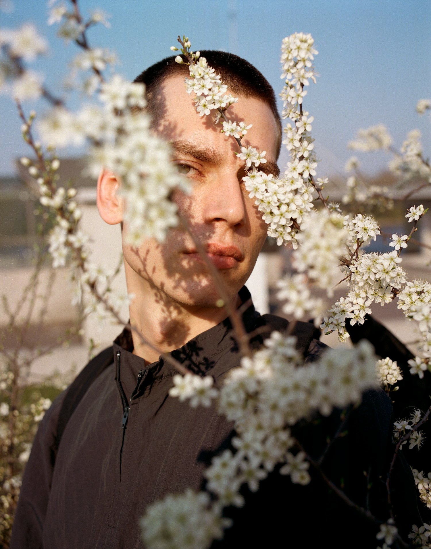 Thisispaper Bags & Backpacks Collection by Thisispaper Studio — A portrait from the Thisispaper Bags & Backpacks Collection featuring a figure positioned among white flowering branches in full bloom.