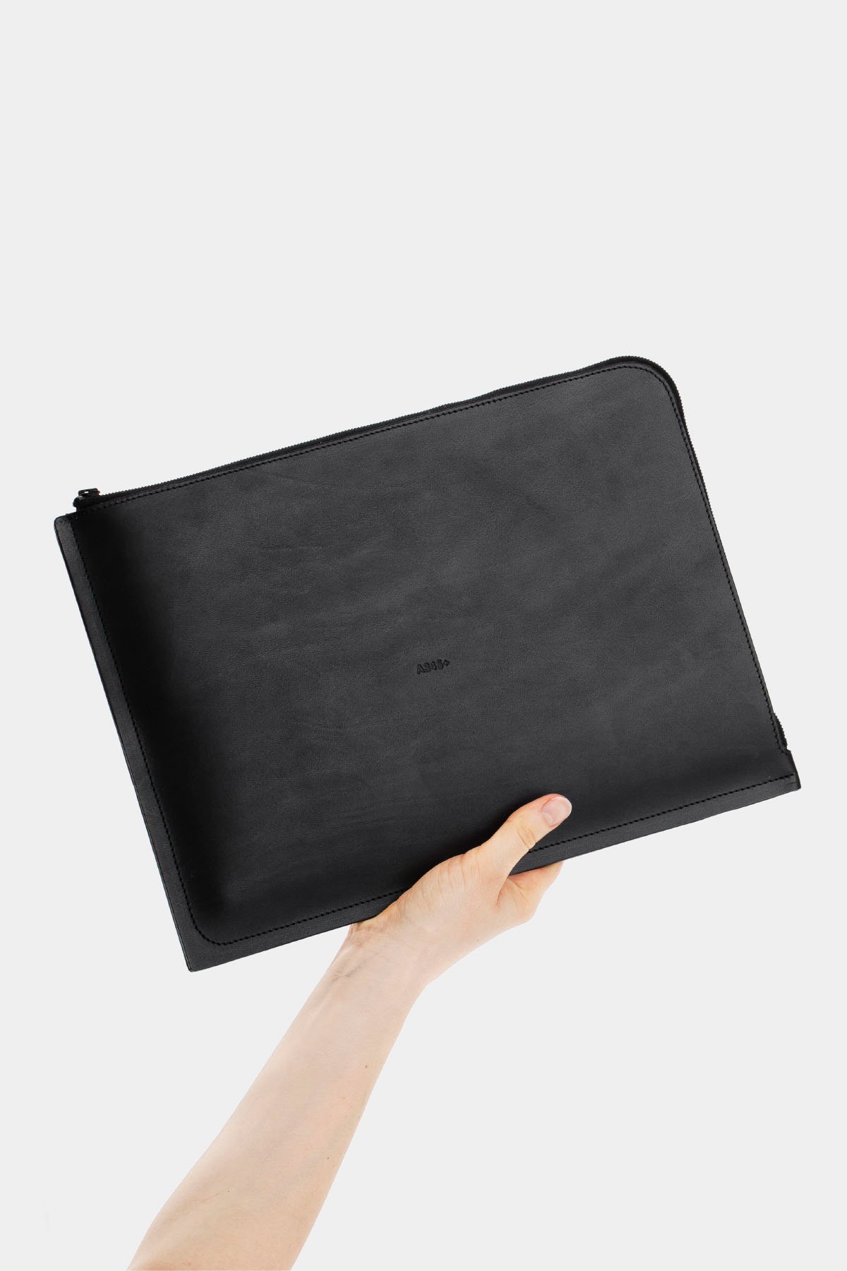 A345+ by Thisispaper Studio — A345+ leather pouch held aloft against neutral backdrop, showcasing the refined minimalism of the accessory line.
