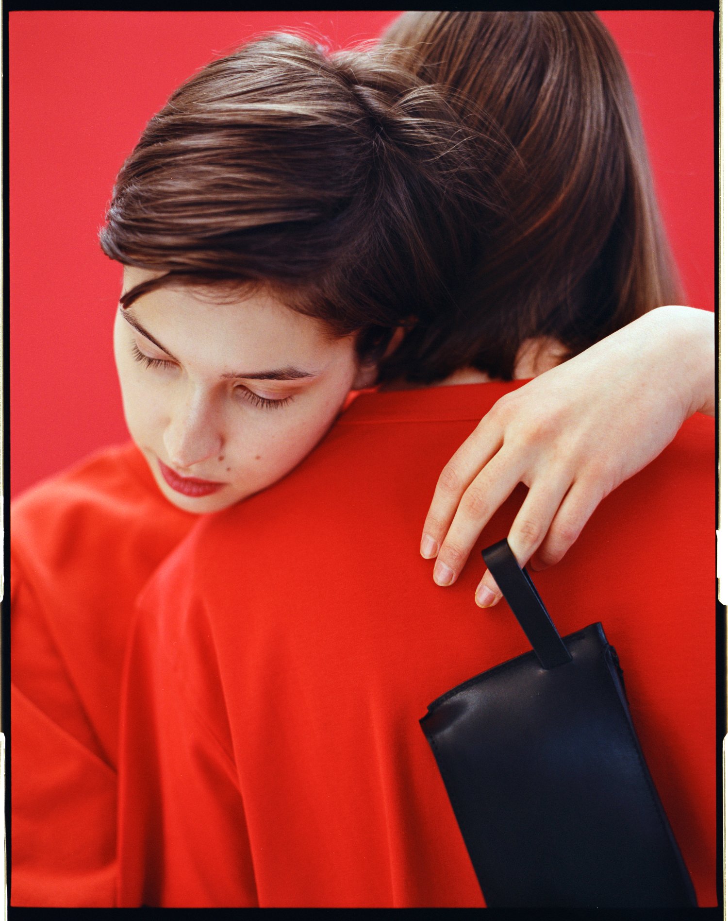 Yenisei by Thisispaper Studio — Product photography isolates a black leather tote against a vibrant red background, emphasizing the accessory's minimal form and material tactility.