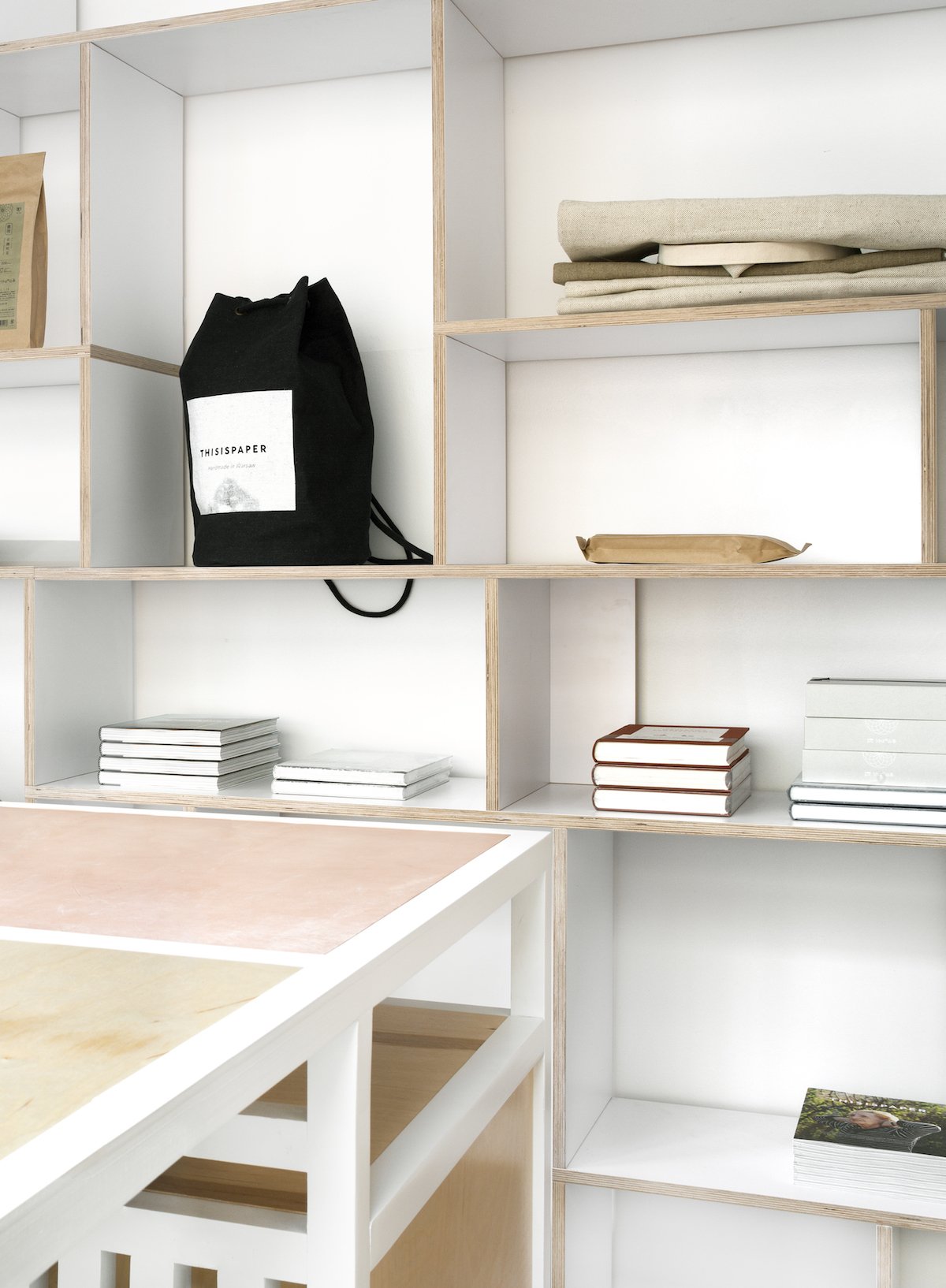 Thisispaper Warsaw Flagship Store by Thisispaper Studio — Shelving detail within the Thisispaper Warsaw flagship store interior, showing a modular plywood storage system with horizontal divisions and birch timber...