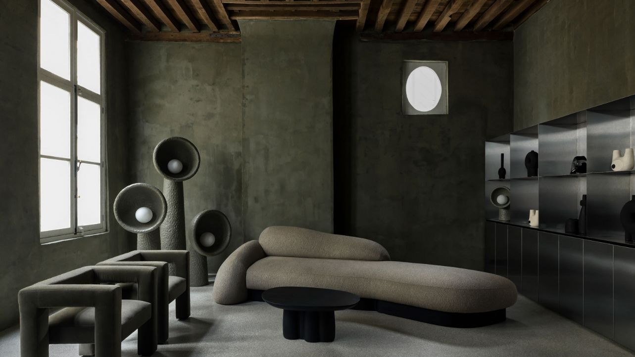 Faina Gallery by Yakusha Studio — The gallery interior showcases hand-rendered charcoal walls with visible trowel marks beneath exposed timber joists with dark stain.
