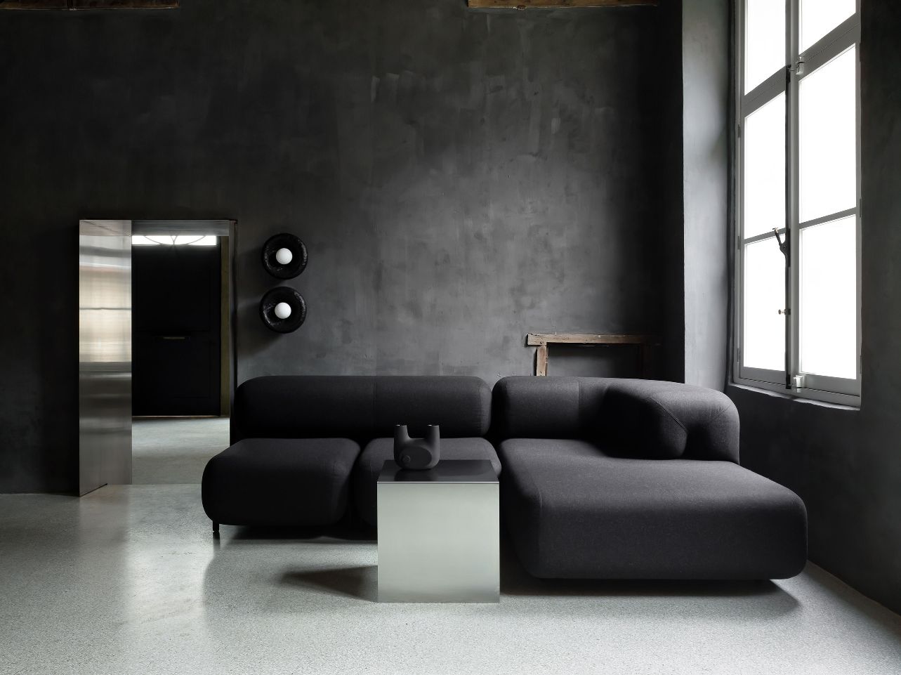 Faina Gallery by Yakusha Studio — Faina Gallery's ground floor showcases a sculptural seating arrangement within a hand-rendered charcoal-grey interior.