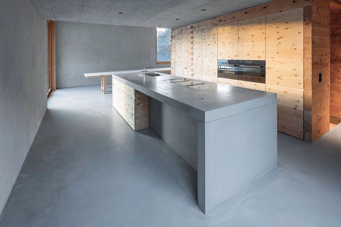 The Trin Cabin By Schneller Caminada Architects — Interior view of the Trin Cabin's kitchen zone, revealing the spatial organization across the open-plan ground floor.