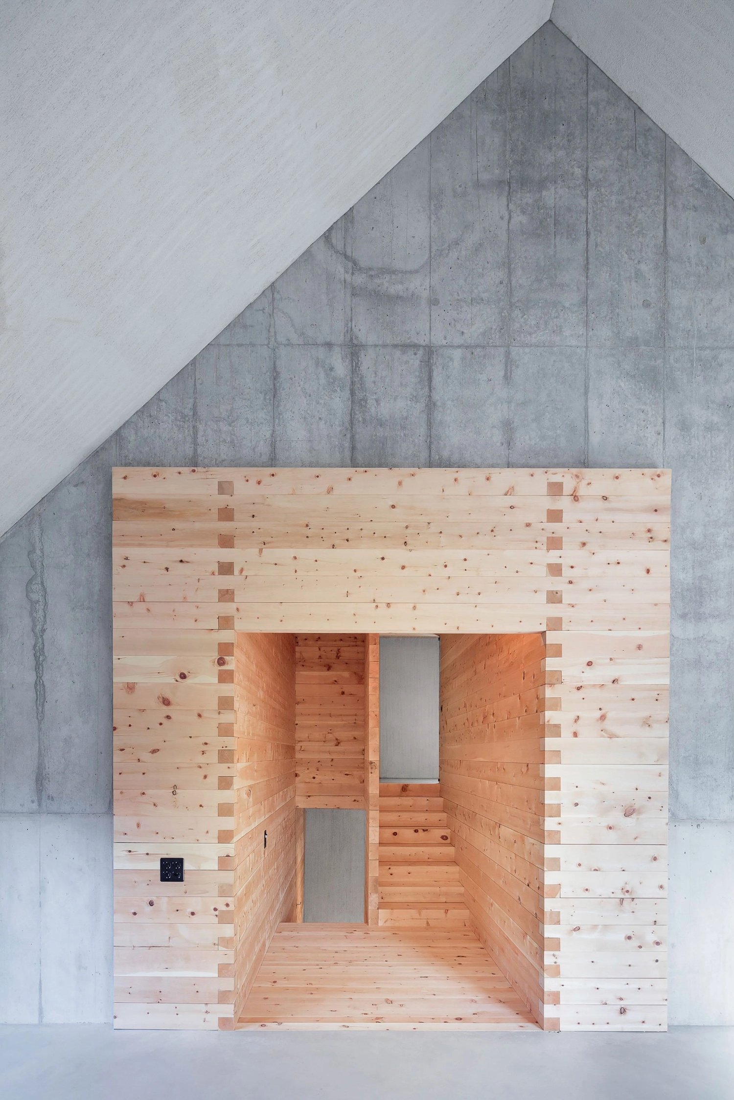 The Trin Cabin By Schneller Caminada Architects — Interior view of a timber-framed pavilion with light pine board construction.