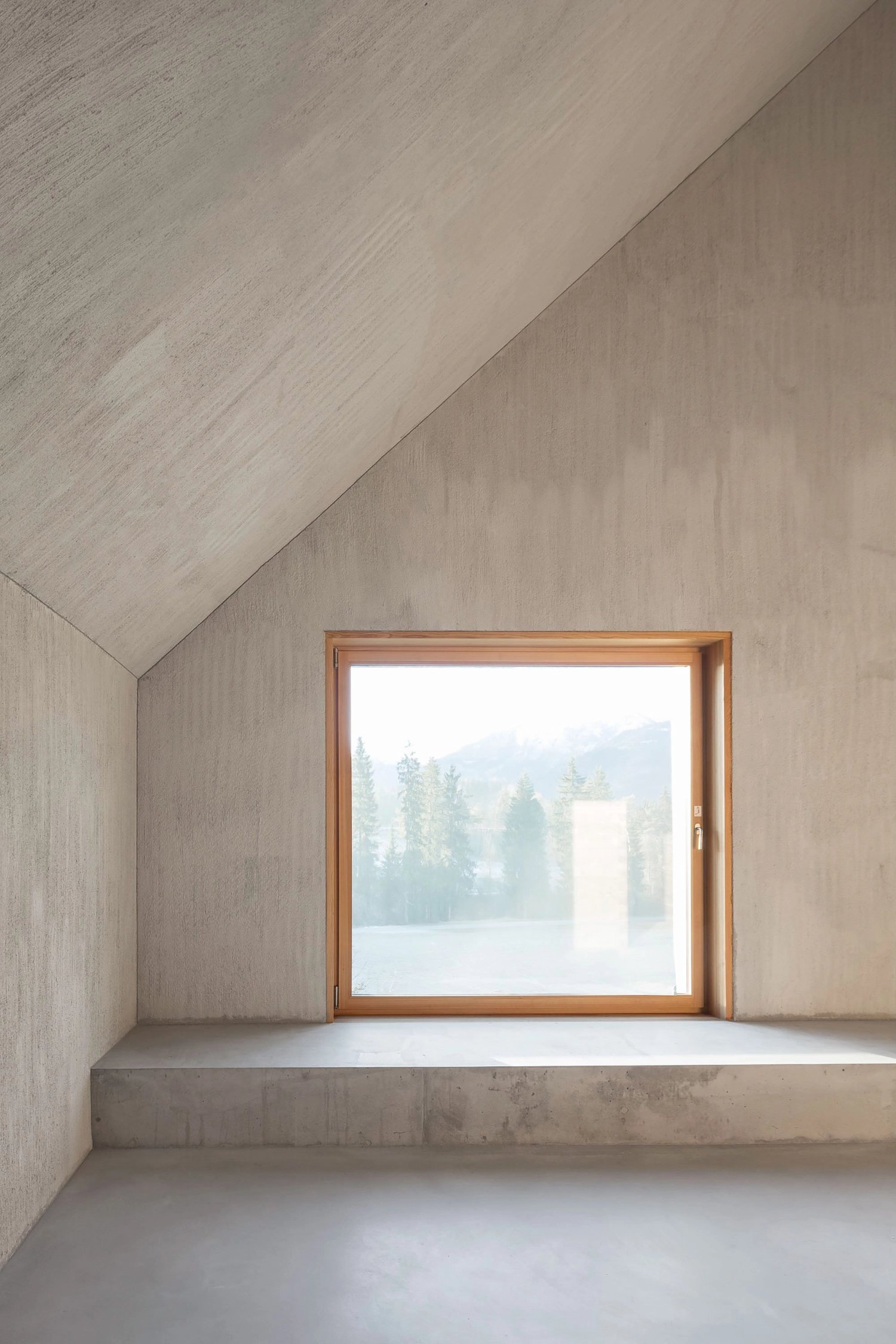 The Trin Cabin By Schneller Caminada Architects — A three-story interior space within the Trin Cabin showcases the architect's fenestration strategy, with a substantial timber-framed window dominating the...