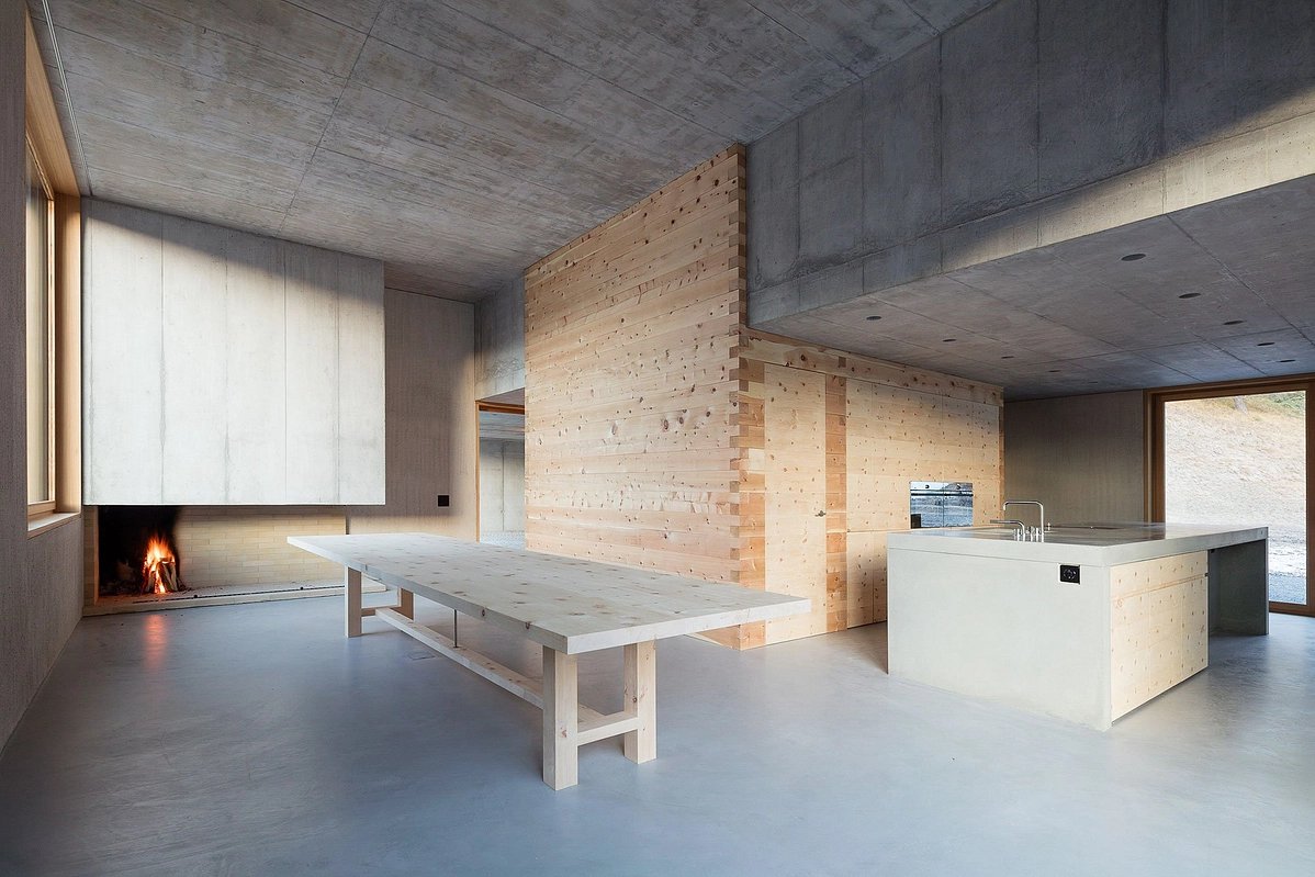 The Trin Cabin By Schneller Caminada Architects — Interior view of the Trin Cabin revealing a three-story open volume defined by board-formed concrete ceiling and walls.