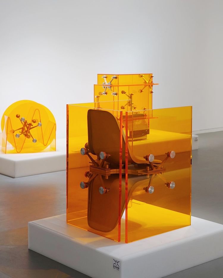 Mixed Public-Private Boundary collection by Cometabolism Studio — Cometabolism Studio's translucent orange and amber acrylic enclosure contains visible mechanical components and industrial hardware mounted on internal...