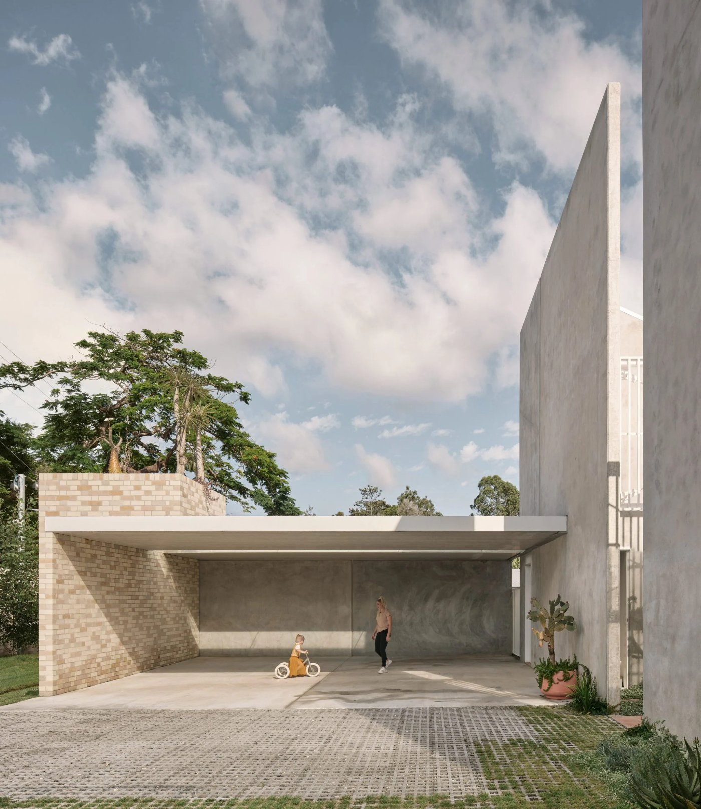 Chelmer River House by Furminger by Christopher Furminger — A low-angle view into the open courtyard garden, framed by the curved brick-clad structure on the left and the monolithic tilt-up concrete panel rising...