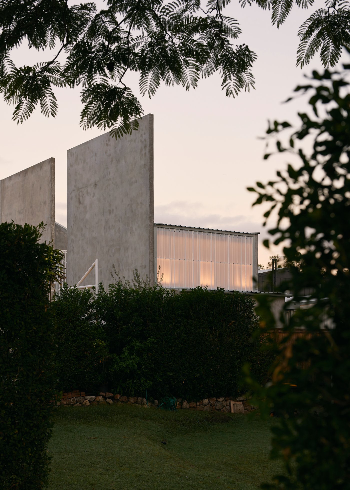 Chelmer River House by Furminger by Christopher Furminger — Evening light illuminates the corrugated translucent polycarbonate wall of the Chelmer River House, revealing interior warmth against the cooling dusk sky.