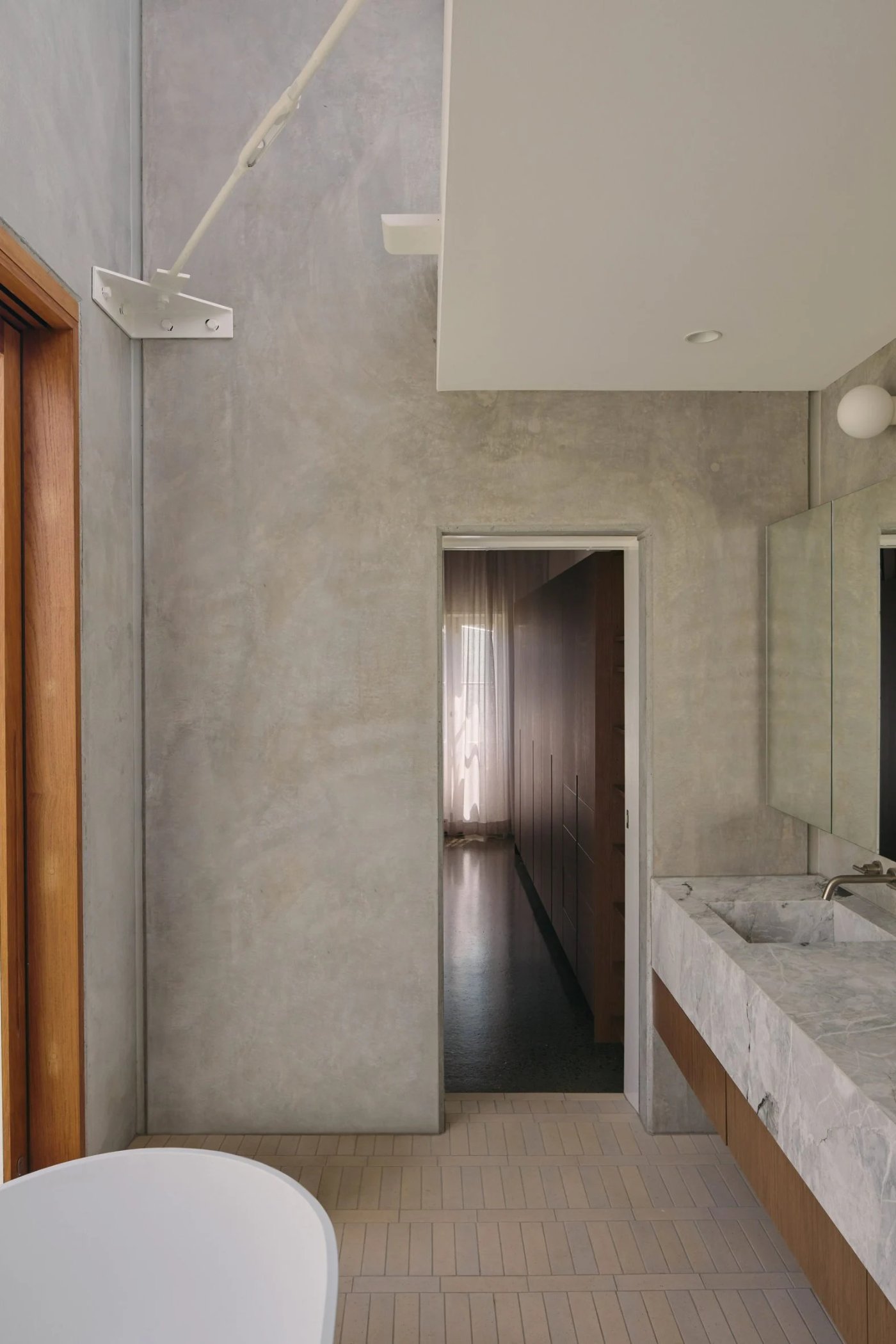 Chelmer River House by Furminger by Christopher Furminger — Interior bathroom passage in rendered concrete, featuring monolithic wall planes rising to full height with minimal openings.