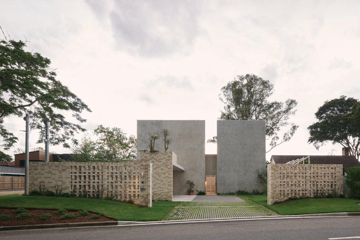 Chelmer River House by Furminger by Christopher Furminger — Chelmer River House presents a symmetrical garden facade framed by two brick-clad perimeter walls with deep grid-pattern fenestration.