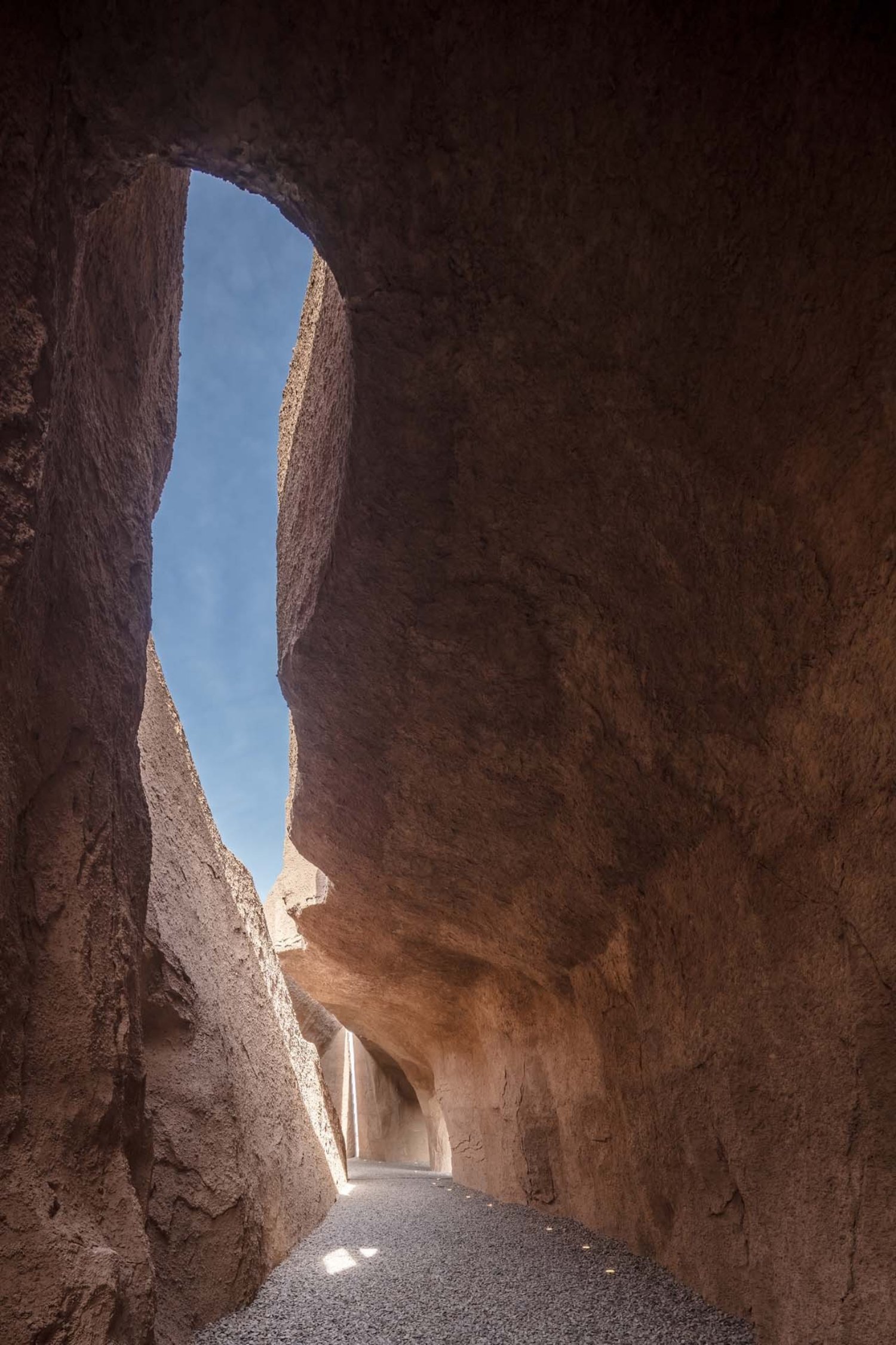 Holy Fire Lit Place in China by URBANUS — A narrow earthen passage carved through monolithic rammed-earth walls demonstrates the museum's excavation strategy.