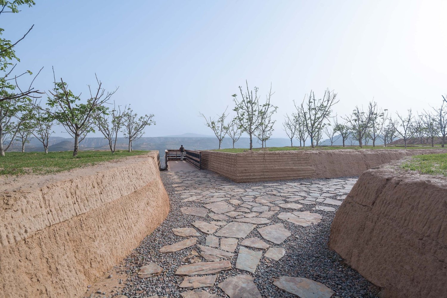 Holy Fire Lit Place in China by URBANUS — A rammed-earth passage carved through monolithic earthen walls demonstrates the museum's geological vocabulary.