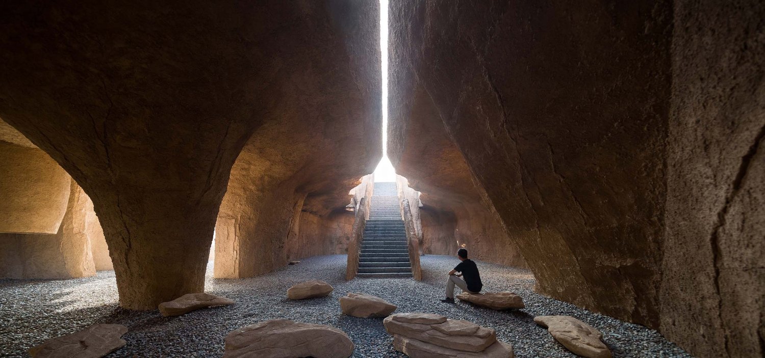 Holy Fire Lit Place in China by URBANUS — A cavernous interior carved from monolithic earthen mass, its walls textured with natural geological stratification.