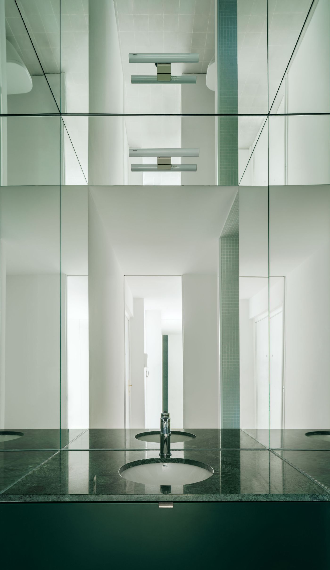 Lara House by HANGHAR — A bathroom interior organized around symmetrical vertical axes, with paired circular basins anchoring a dark stone countertop.