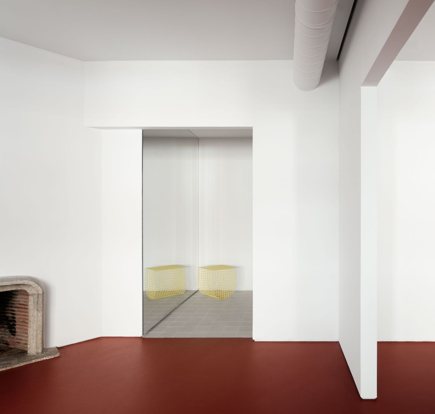 Lara House by HANGHAR — A minimalist corridor interior anchored by a recessed doorway with glass sliding panels reflecting yellow wire-mesh seating.