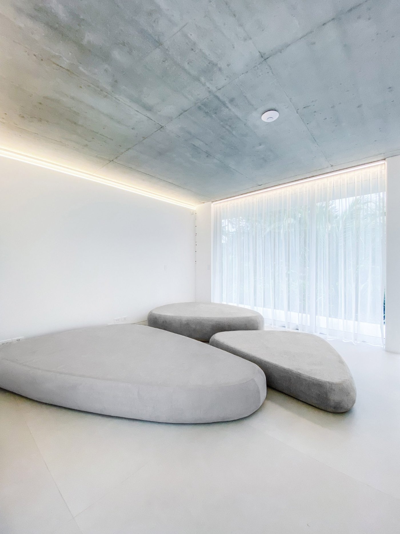 Magnolia House by Estudio Felipe Escudero — A minimalist interior defined by three sculptural concrete pods arranged across a polished concrete floor.